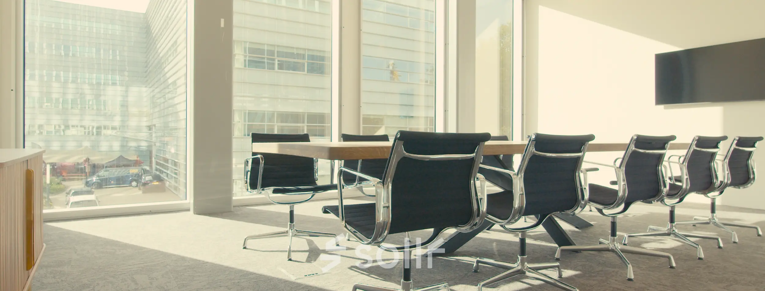 Modern conference room with large windows overlooking Amsterdam Riekerpolder, featuring a sleek table and chairs, available for office space rental.