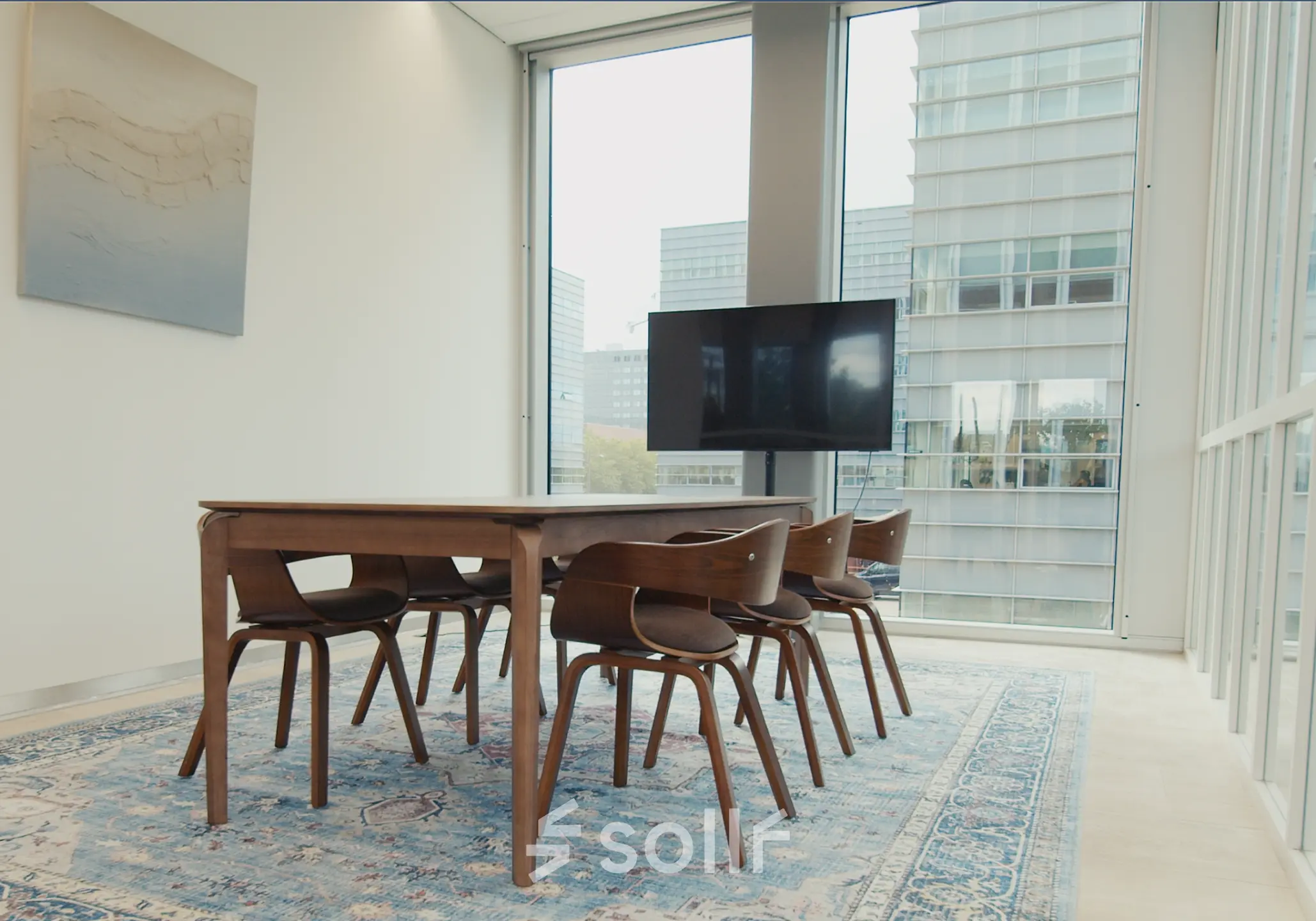 Bright conference room with a large wooden table, six chairs, and a wall-mounted screen, located in an office to rent at David Ricardostraat 1, Amsterdam Riekerpolder.