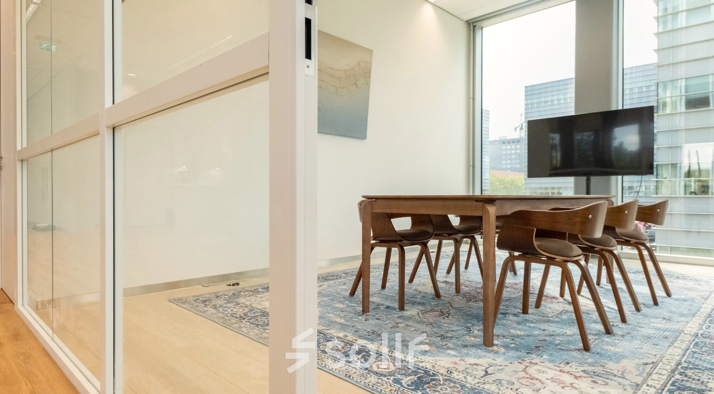 Bright office space in Amsterdam Riekerpolder at David Ricardostraat 1, featuring a conference room with a wooden table, chairs, and large windows.