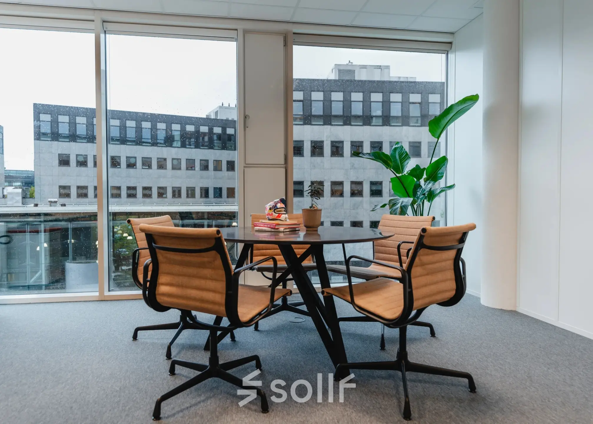 Bright office space with a round table and four chairs near large windows, located at John M. Keynesplein 4-10, an ideal spot for those seeking office space rental in Amsterdam Riekerpolder.