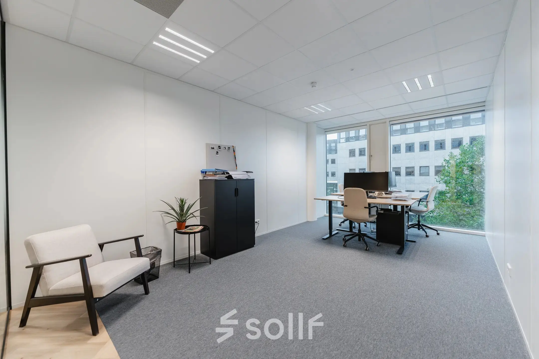 Furnished office space at John M. Keynesplein 4-10, Amsterdam Riekerpolder, featuring a desk, chairs, and cabinets near a large window with city views.