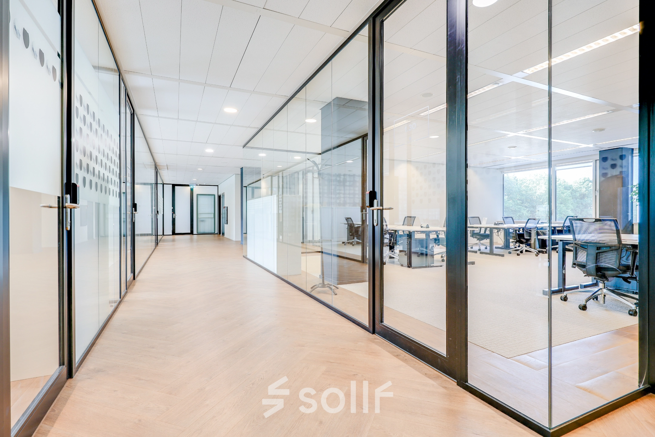 Bright hallway leading to furnished office spaces with glass partitions, ideal for office space rental in Amsterdam Riekerpolder.