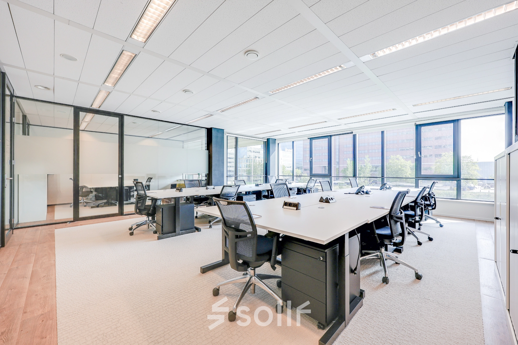 Bright office space for rent in Amsterdam Riekerpolder with desks, chairs, and large windows offering city views.