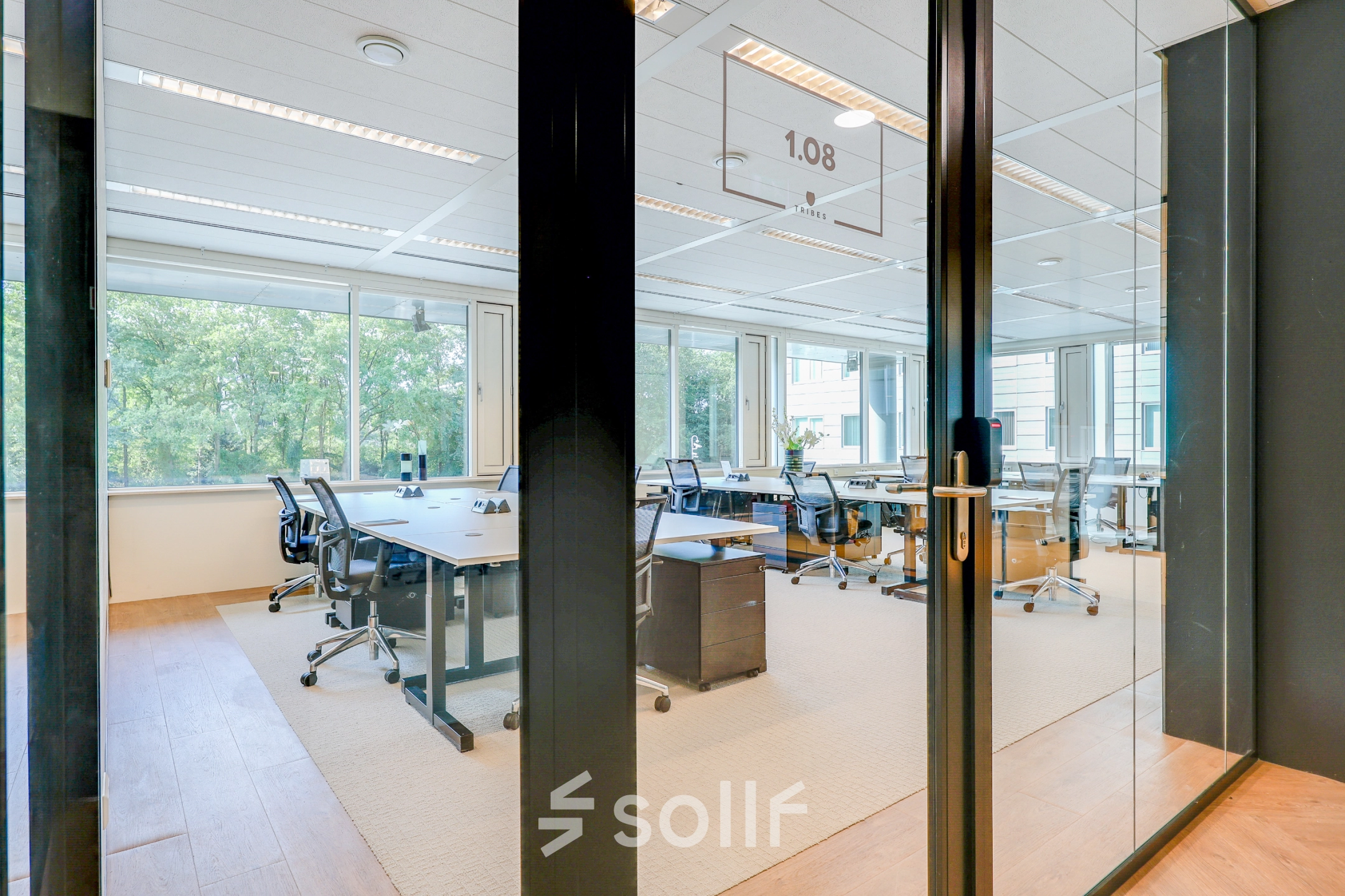 Spacious office space to rent in Amsterdam Riekerpolder, featuring large windows, multiple desks, and ergonomic chairs, offering a bright and professional workspace.