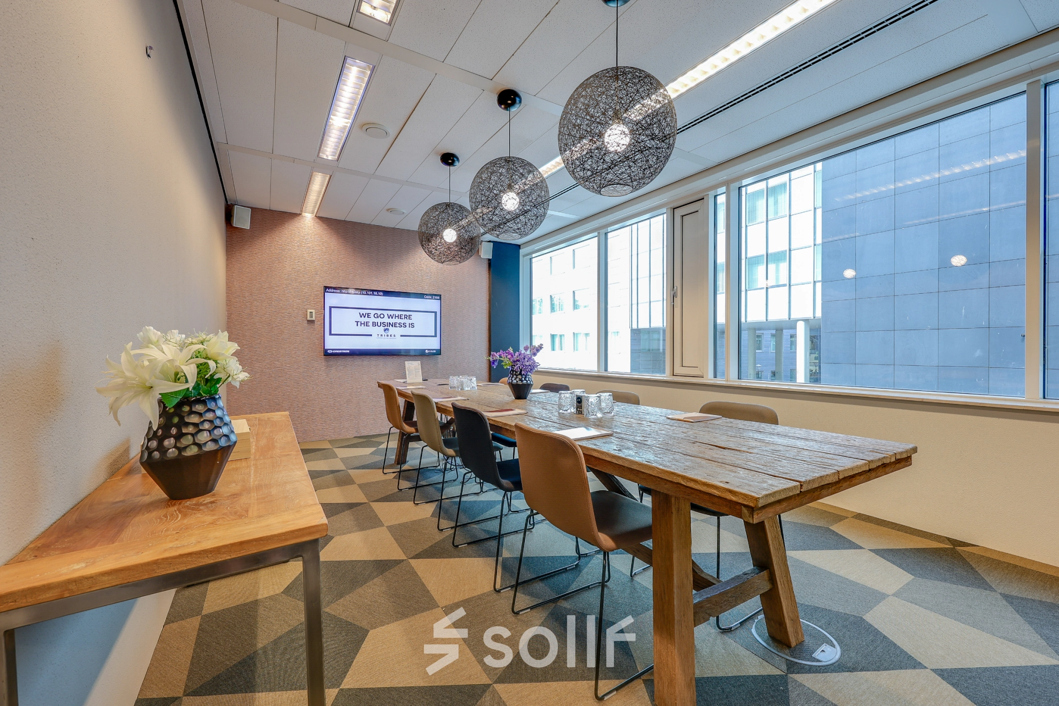 A stylish conference room at Thomas R. Malthusstraat 1-3 in Amsterdam Riekerpolder, featuring a long wooden table, chairs, and pendant lighting, perfect for office space rental.