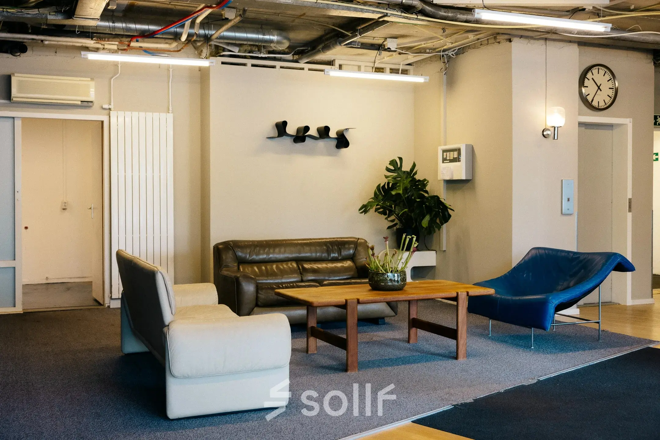 Interior view of a furnished office lounge at Kabelweg 24, Amsterdam Sloterdijk, featuring modern seating and a coffee table. Ideal for office space rental.