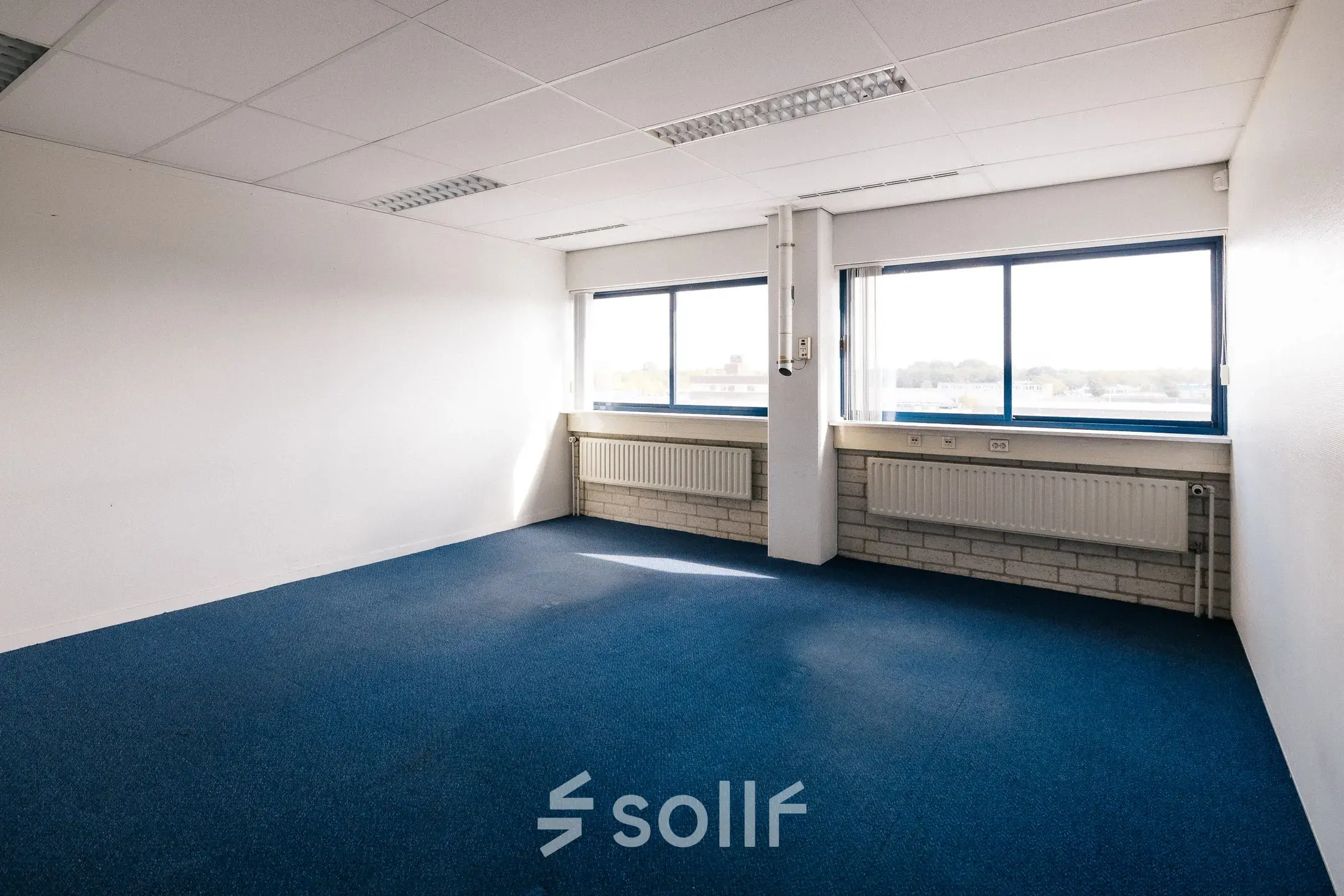 Vacant office space with blue carpet and large windows at Kabelweg 24, Amsterdam Sloterdijk, available for rent.