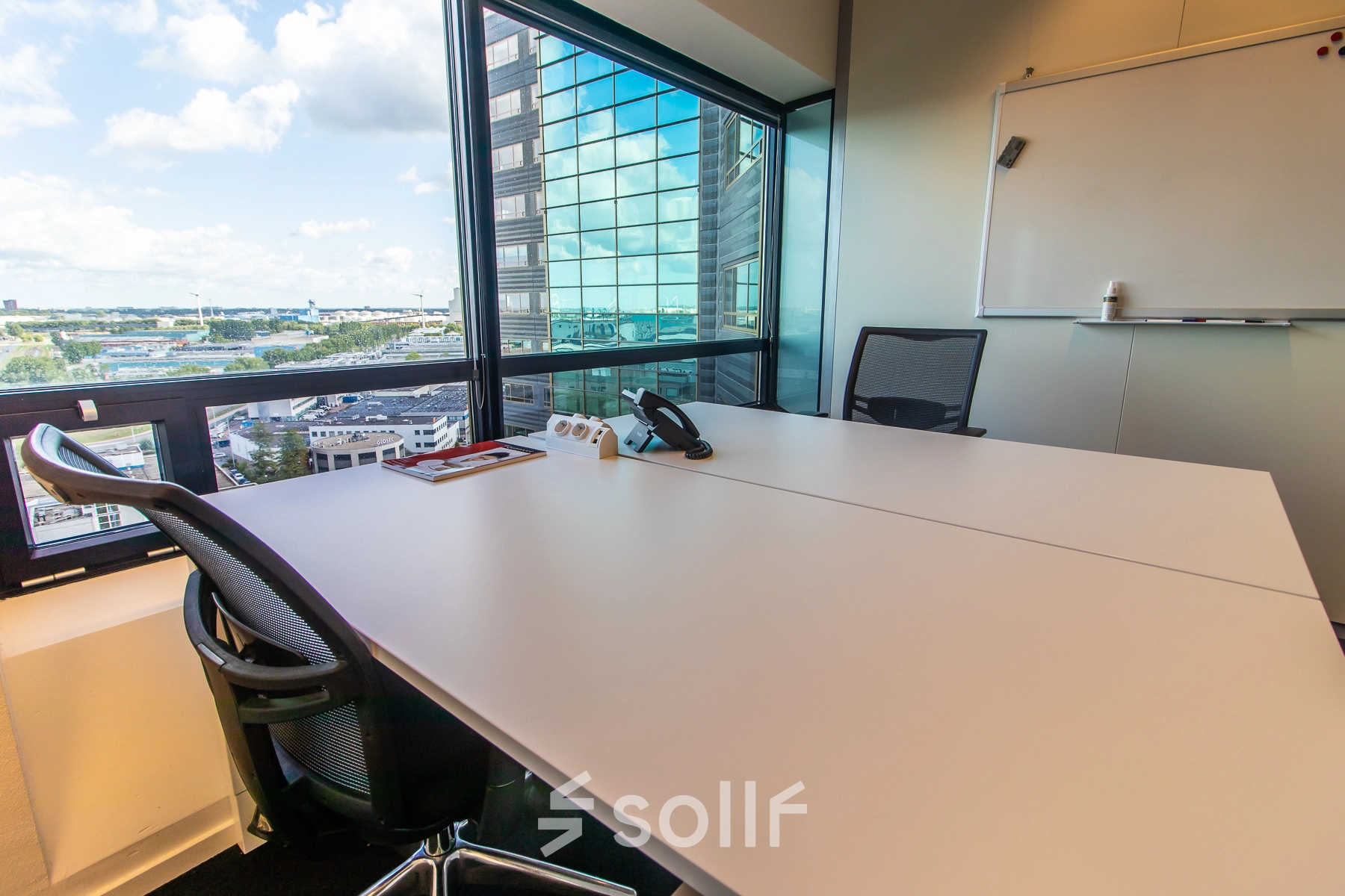 Furnished office space with a large window view at Radarweg 29, Amsterdam Sloterdijk, showcasing a table, chairs, and a whiteboard, perfect for rental.
