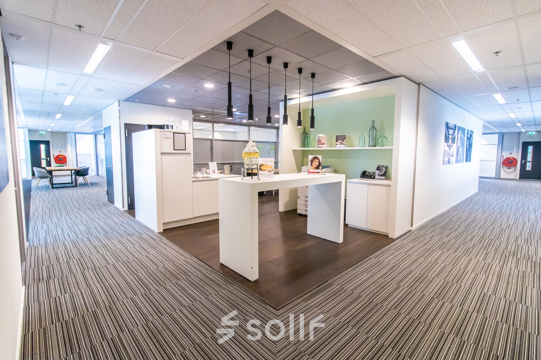 A modern office space at Radarweg 29, Amsterdam Sloterdijk, featuring a furnished area with a central high table and decorative shelves, ideal for office space rental.