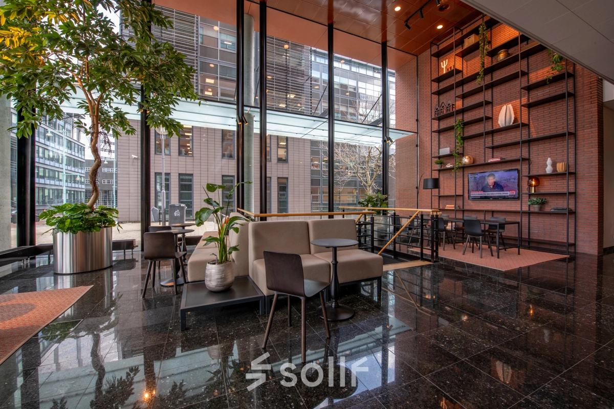 Modern office space for rent at Teleportboulevard 110, Amsterdam Sloterdijk, featuring a stylish furnished interior with seating areas and large windows.
