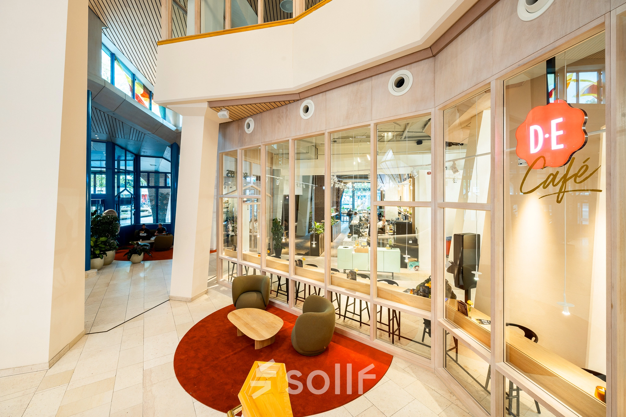 Inviting and modern lobby area with a view into an open office space. Comfortable seating and glass walls enhance the sense of openness, ideal for a collaborative office space rental.