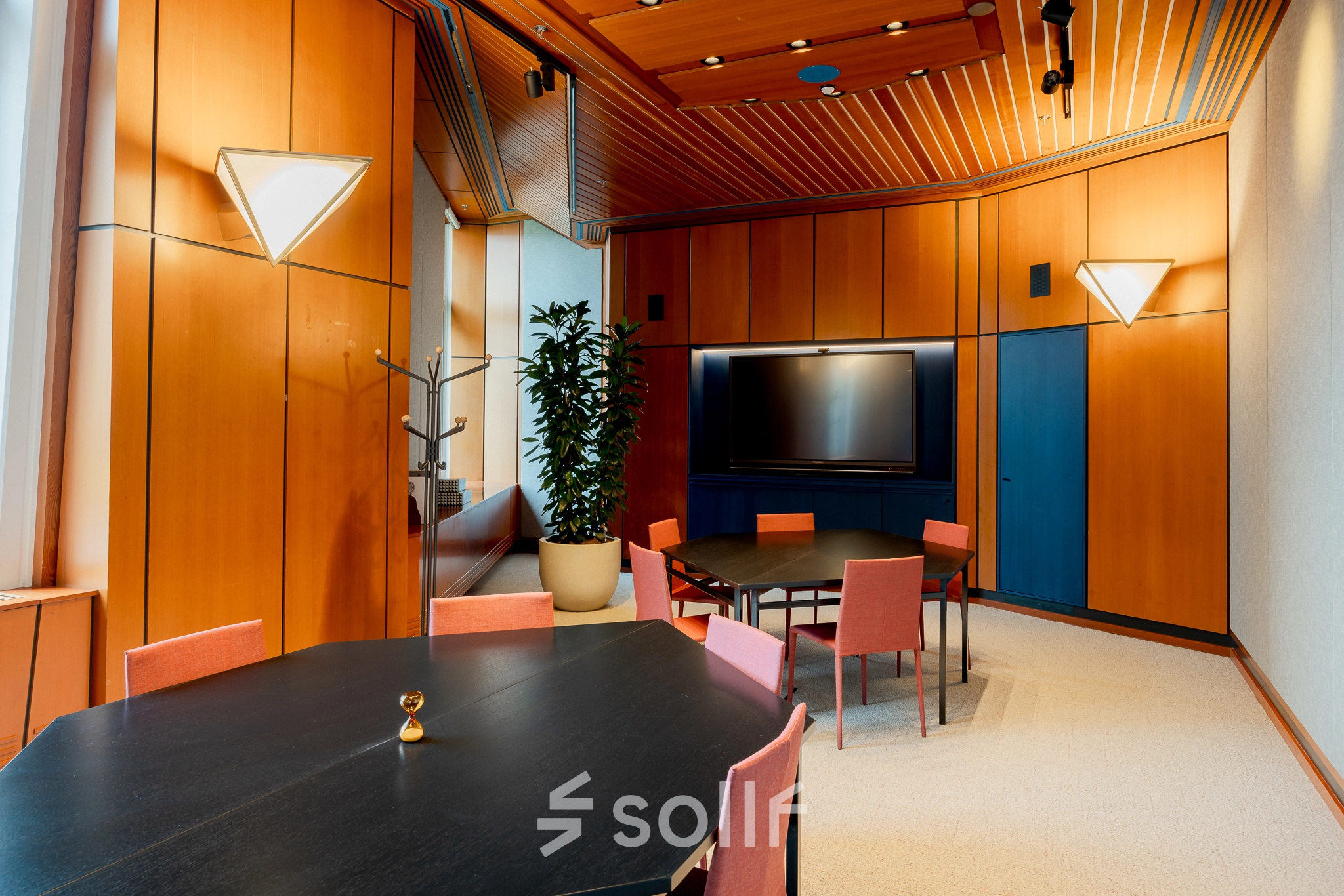 Bright office space at Bijlmerplein 888, Amsterdam South East, featuring stylish wooden walls, modern lighting, and neatly arranged tables for office rental opportunities.
