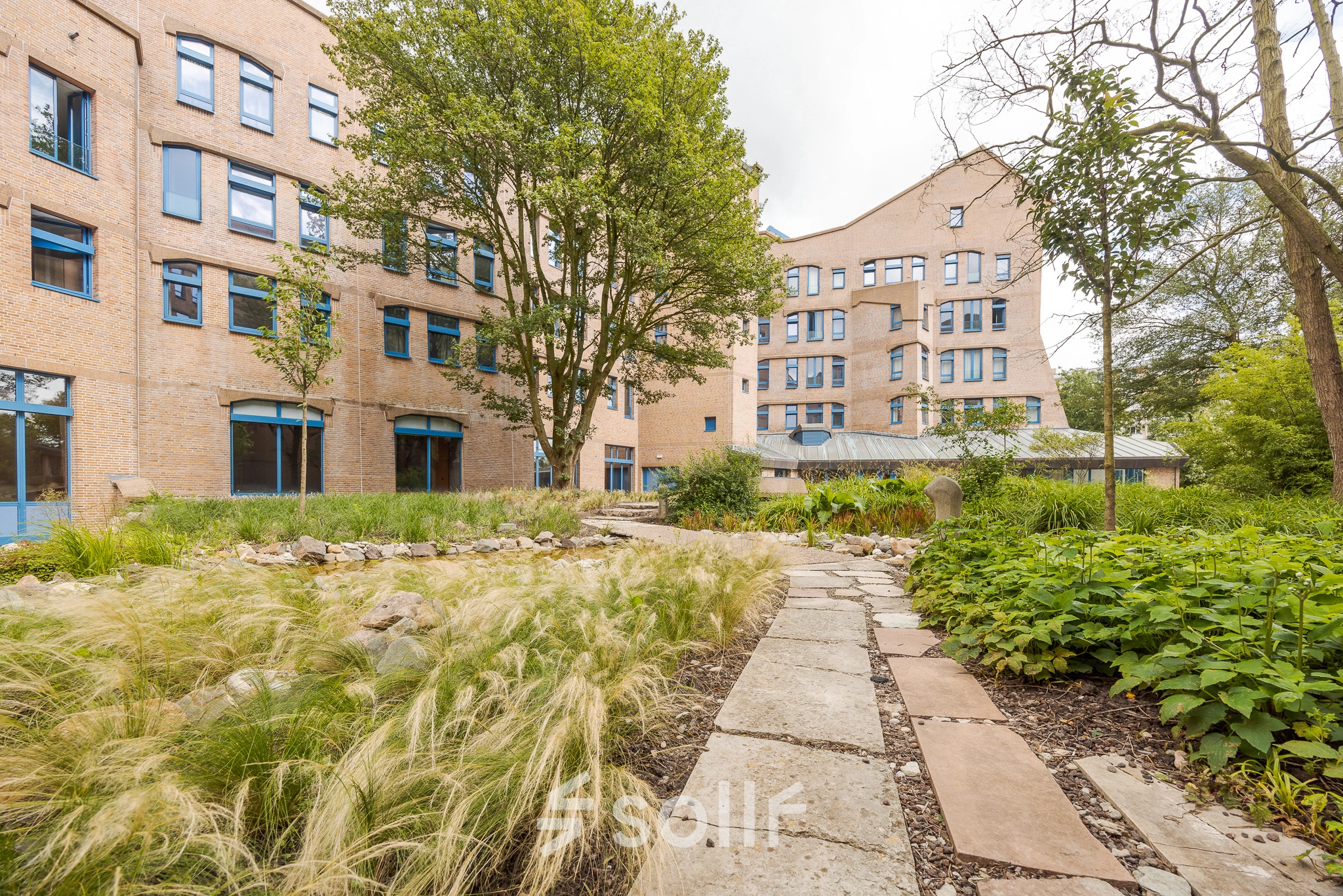 Exterior view of an office building with a garden at Bijlmerplein 888, Amsterdam South East, showcasing the opportunity for office space rental.