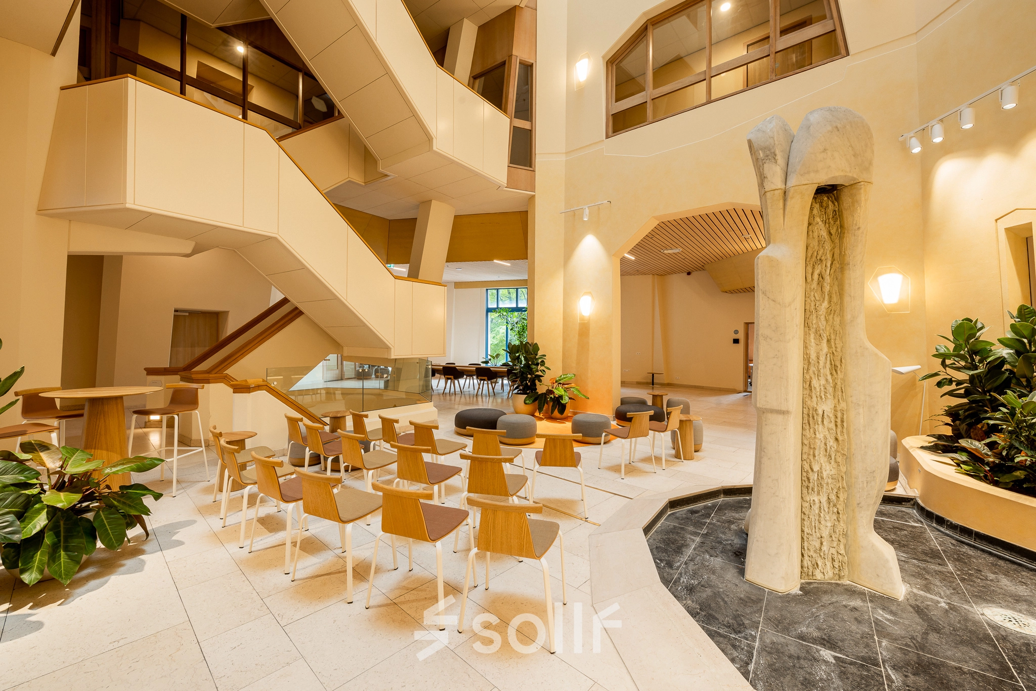 Bright office interior at Bijlmerplein 888, Amsterdam South East, featuring modern seating and a unique stone sculpture, ideal for office space rental or an office to rent.