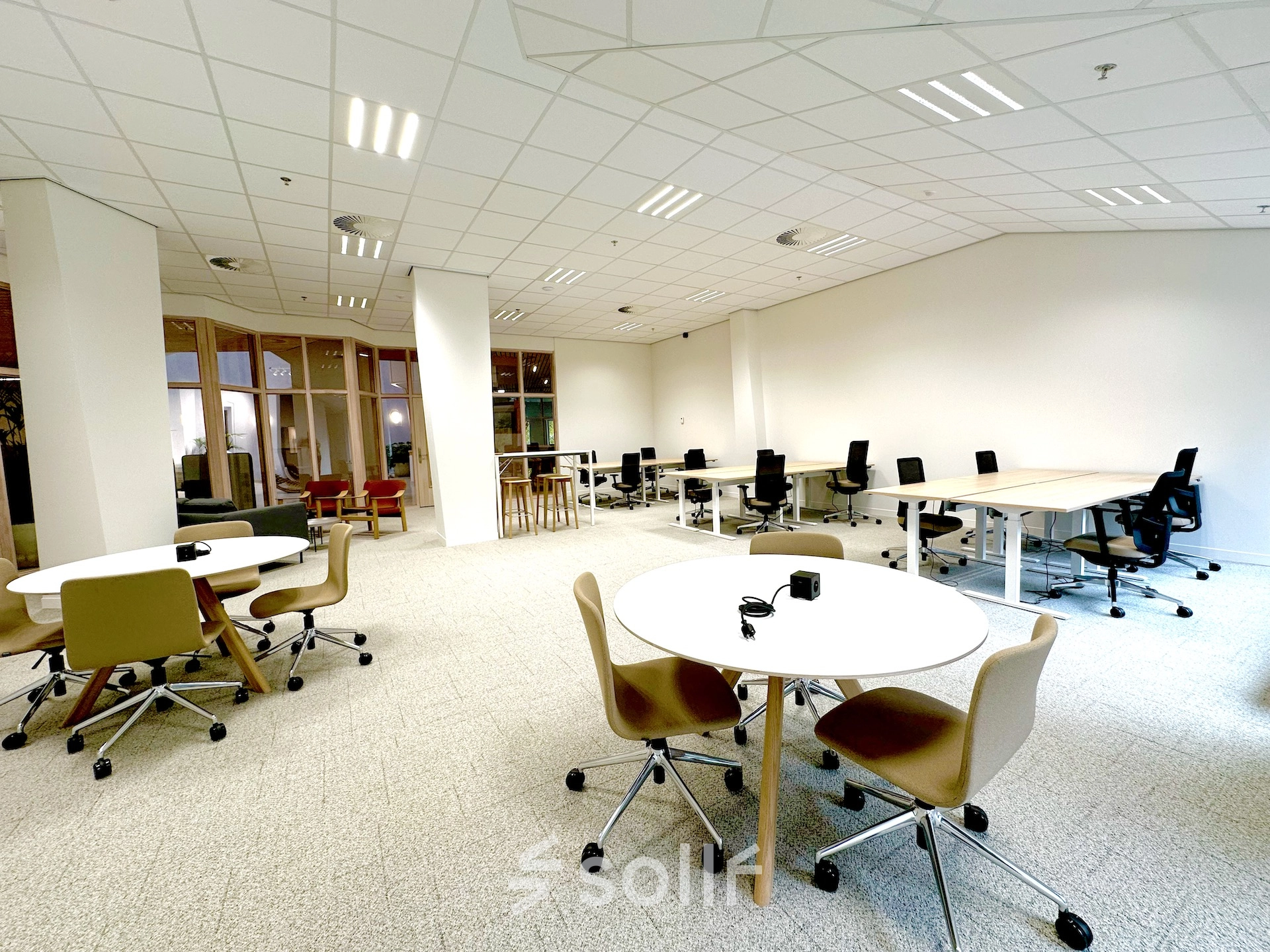 Spacious, well-lit office space with modern furnishings at Bijlmerplein 888, ideal for rent in Amsterdam South East. Features multiple desks and chairs, suitable for various business activities.