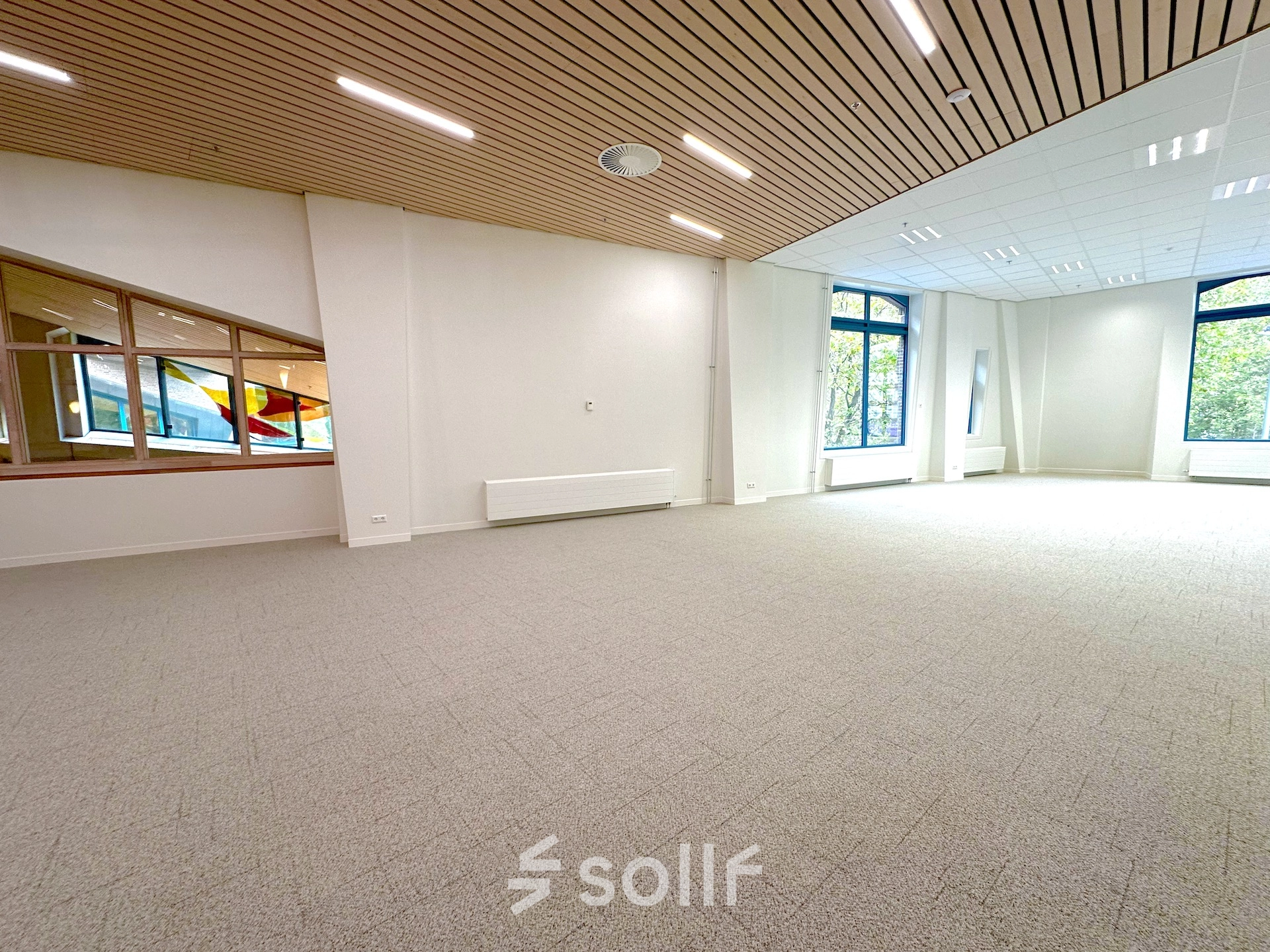 Spacious, well-lit office space available for rent at Bijlmerplein 888, Amsterdam South East, featuring large windows and modern ceiling lights.