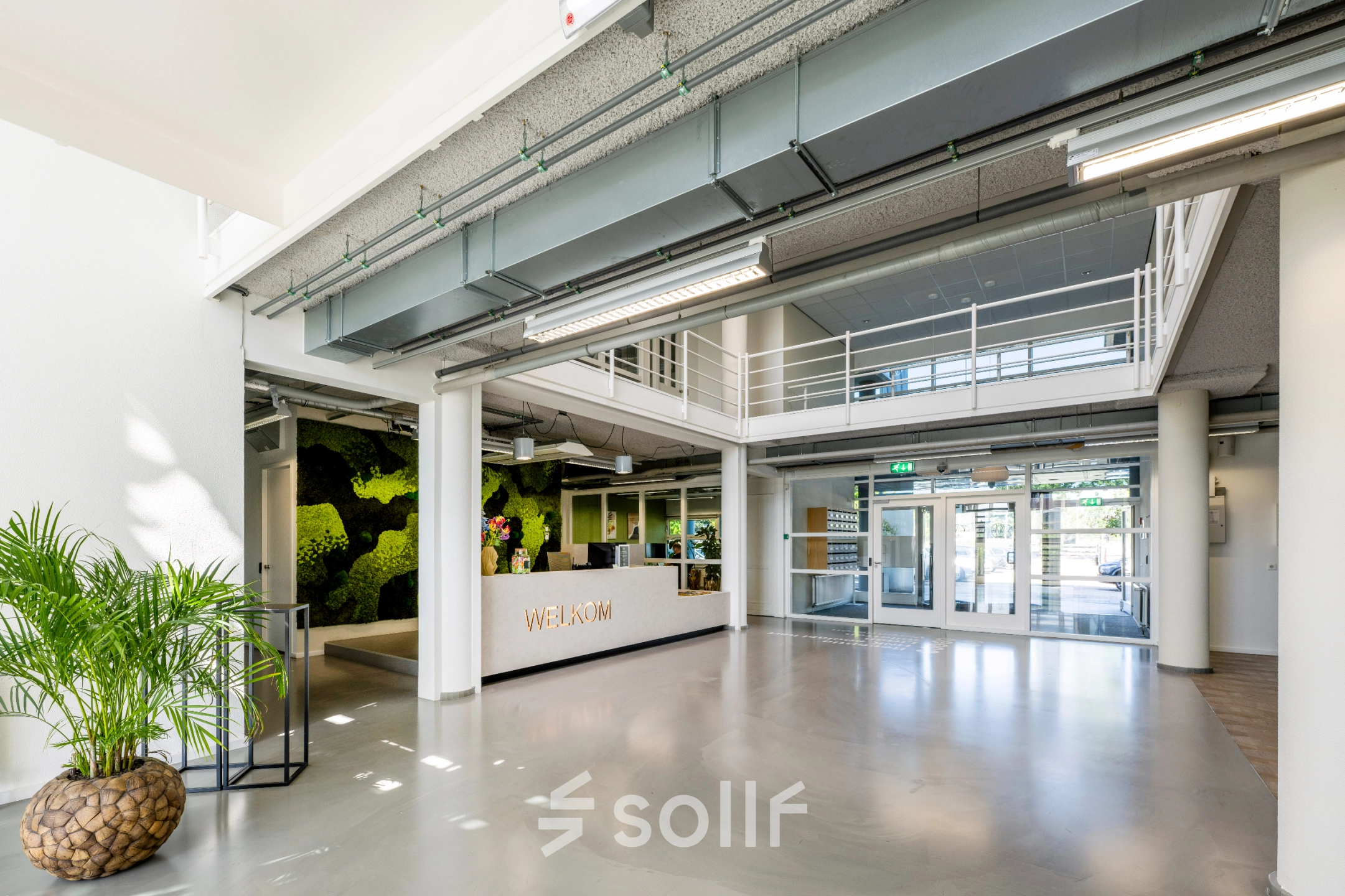 Spacious entrance area of an office to rent at Burgemeester Stramanweg 102, Amsterdam South East, featuring a modern reception desk and greenery for office space rental.