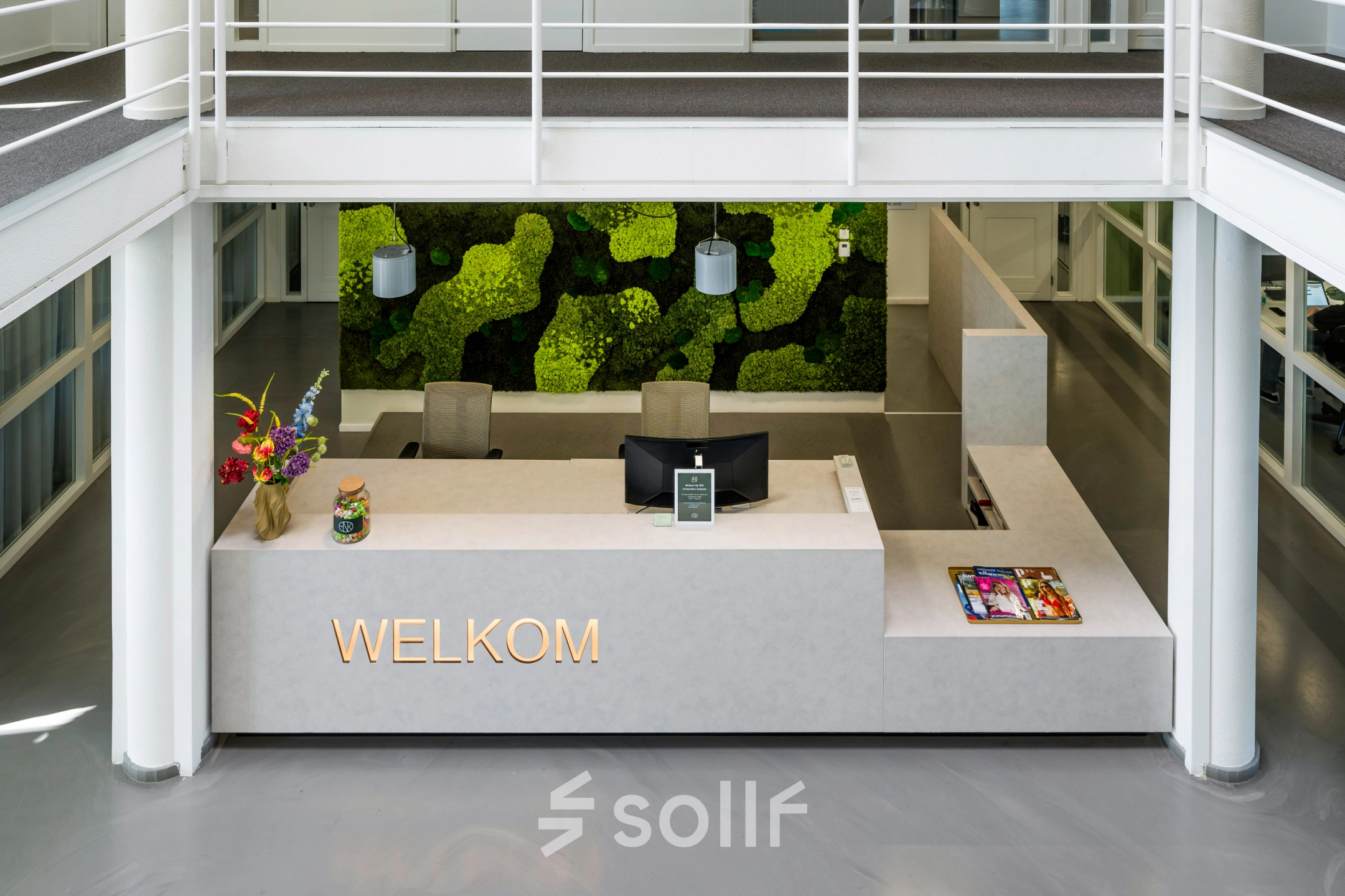 Modern reception area with a green wall and welcome sign at an office to rent in Amsterdam South East.