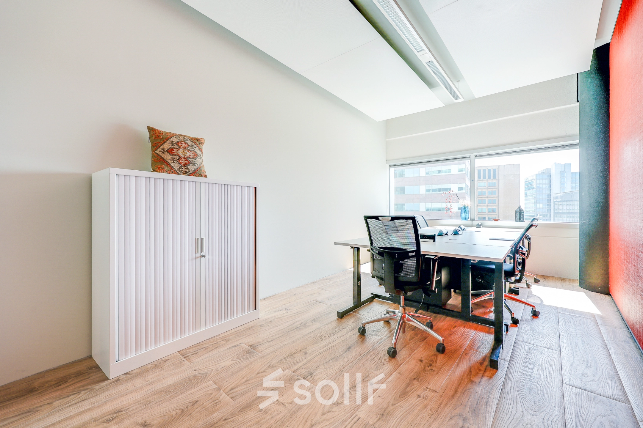Bright office space rental in Amsterdam South East with modern furniture, a large window, and natural light.