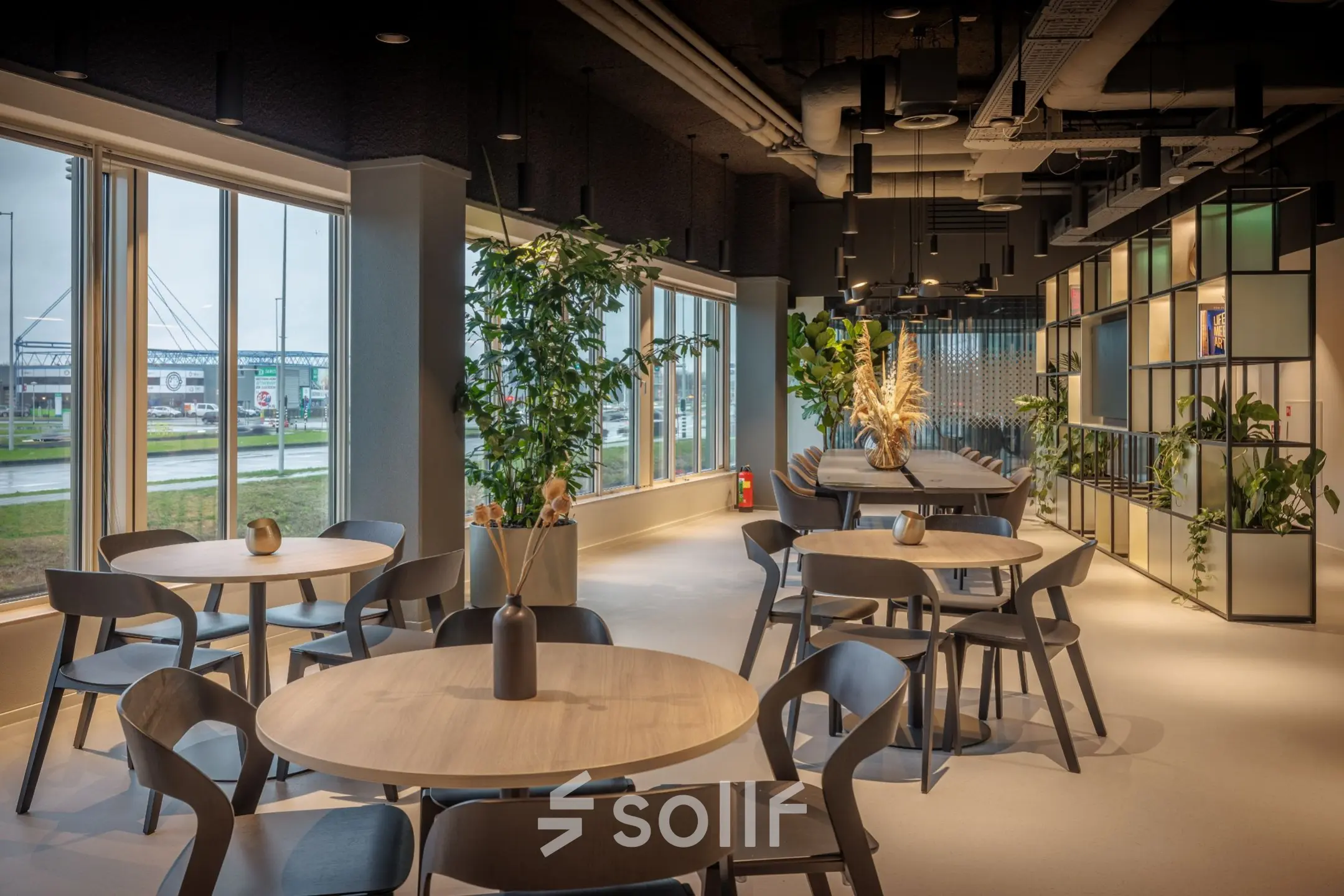 Bright office space in Amsterdam South East with modern decor, round tables, and large windows. Ideal for office space rental.