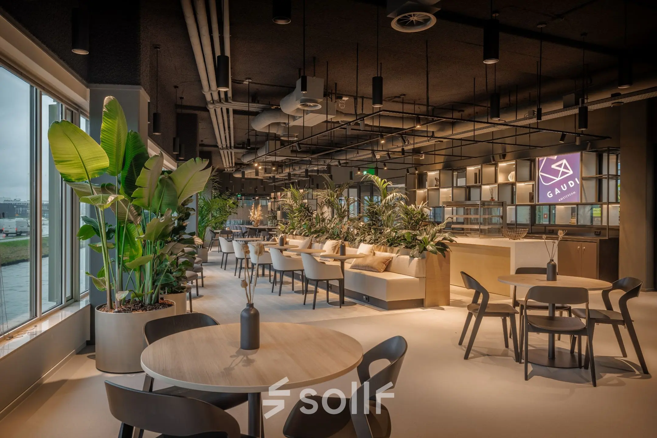 Spacious and modern furnished office space for rent at Herikerbergweg 290, Amsterdam South East, featuring stylish seating and lush greenery, ideal for collaborative workspaces.