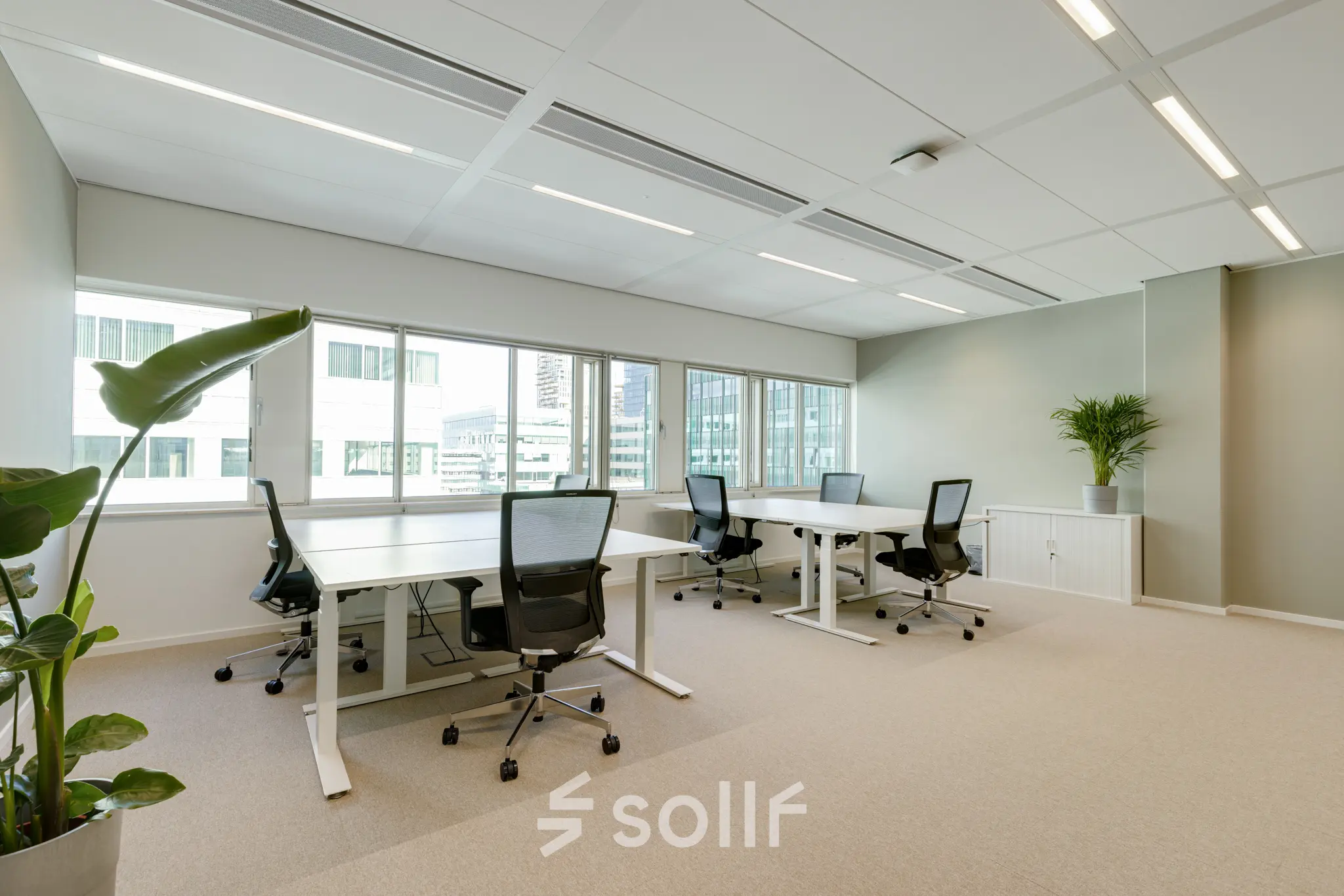 Bright office space for rent at Herikerbergweg 290, Amsterdam South East, featuring modern desks and chairs, with views of surrounding buildings.