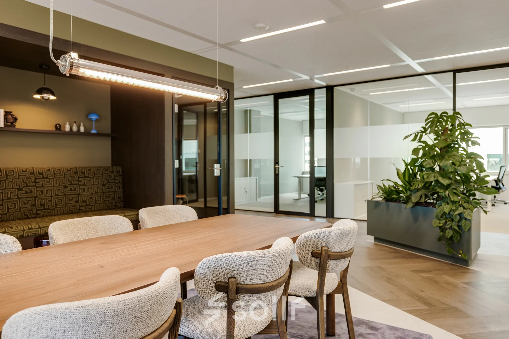 Furnished office space at Herikerbergweg 290 in Amsterdam South East with a large table, chairs, and indoor plants, ideal for those looking to rent office space.