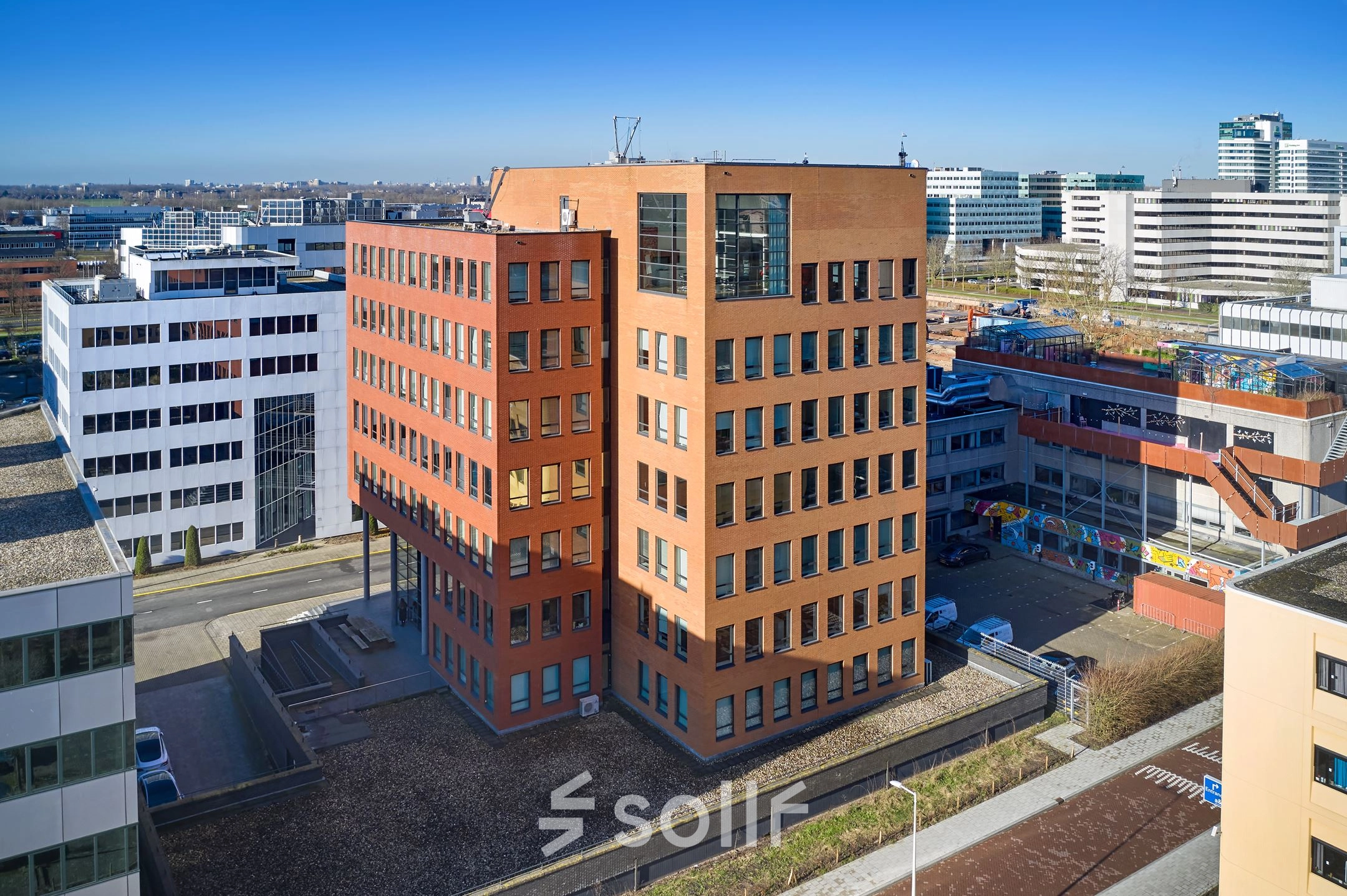 Exterior view of Hogehilweg 24, featuring an office building in Amsterdam South East with red and white facades. Ideal for those seeking office space rental opportunities.