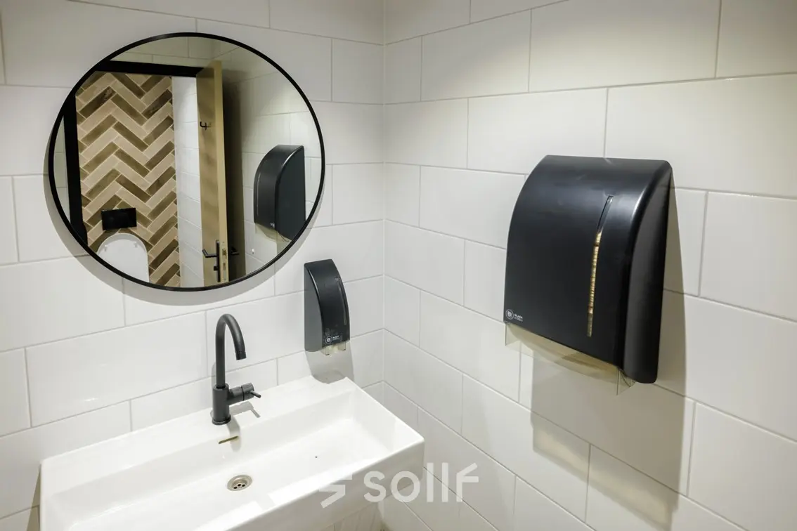 A clean restroom at Hogehilweg 24, Amsterdam South East, suitable for offices to rent, featuring a round mirror and a modern sink.