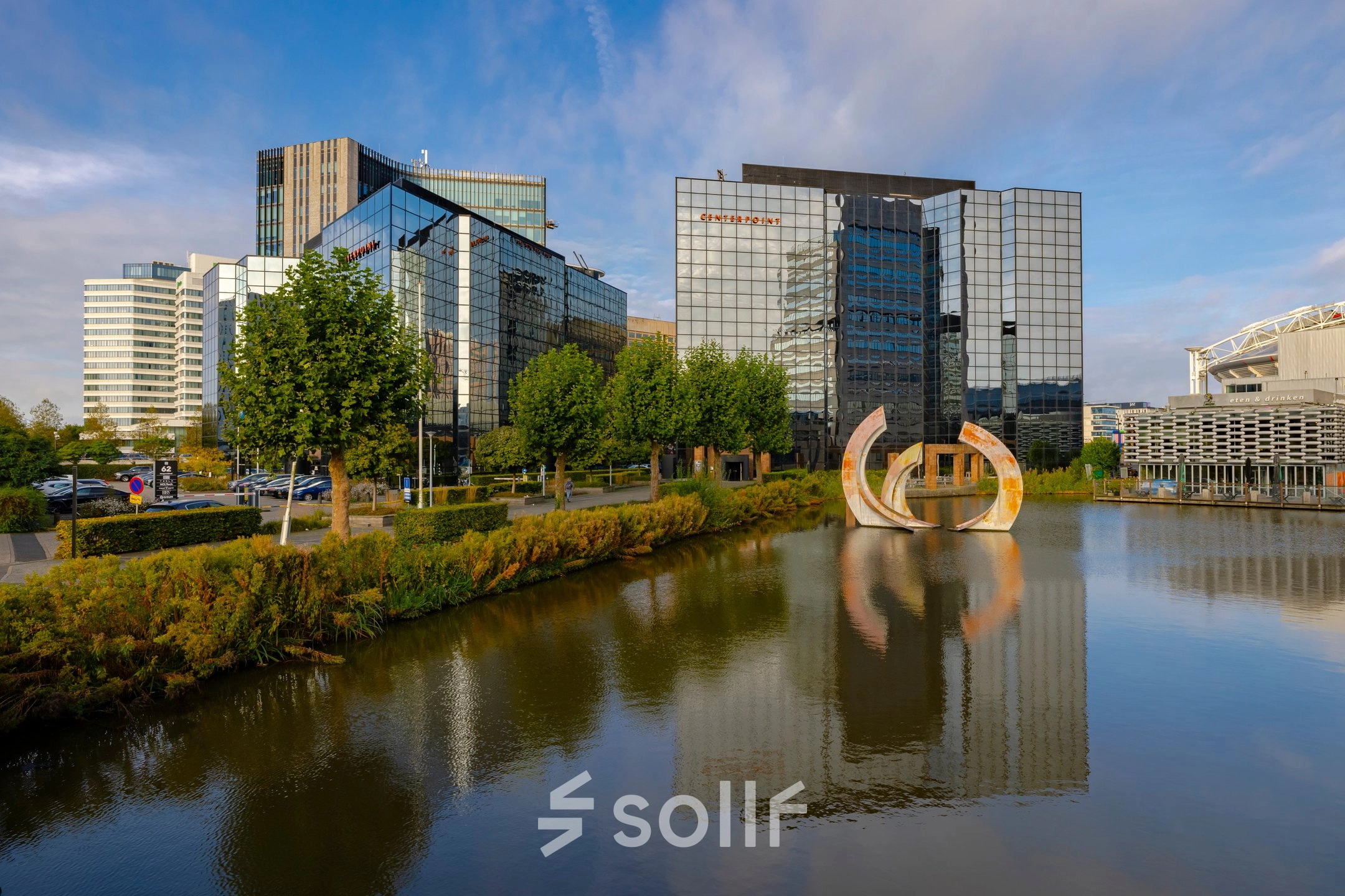 Exterior view of modern office buildings at Hoogoorddreef 60, Amsterdam South East, by a serene pond, ideal for office space rental.