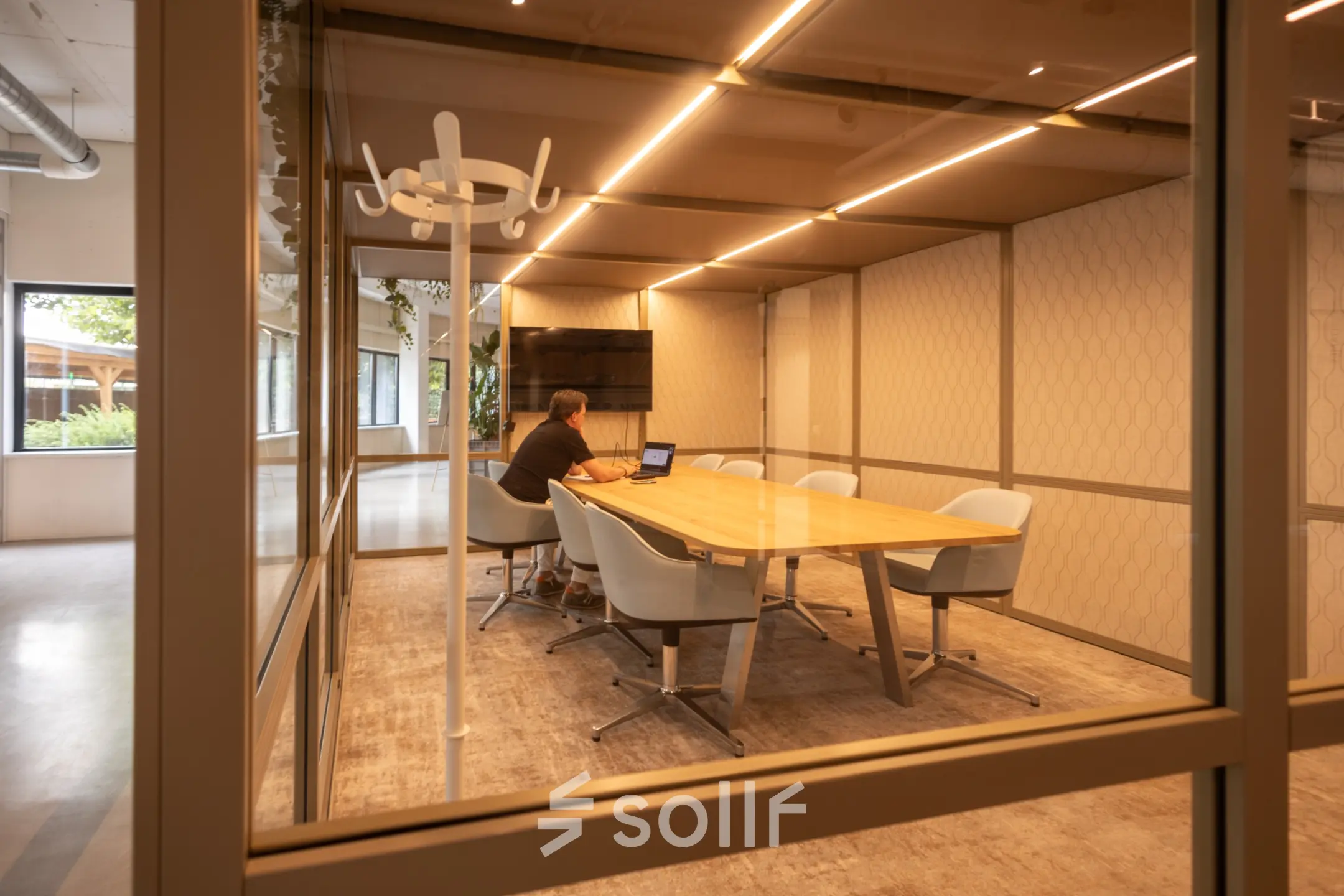 A furnished conference room at Luttenbergweg 8, Amsterdam South East, with a person working on a laptop. Ideal for office space rental or as an office to rent.