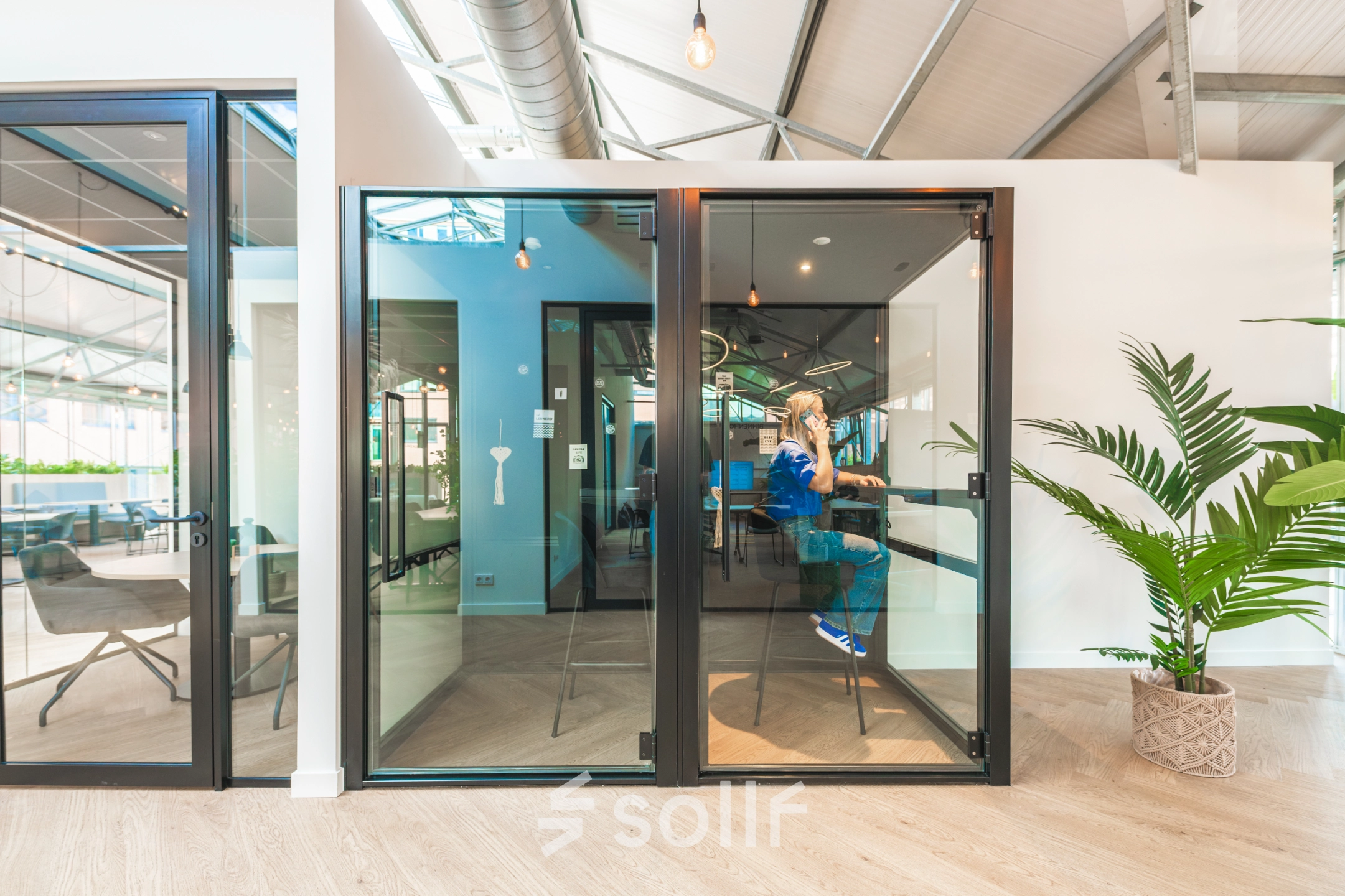 Modern office space at Luttenbergweg 8, Amsterdam South East with glass partitions and a person engaged in business activities, ideal for office space rental.