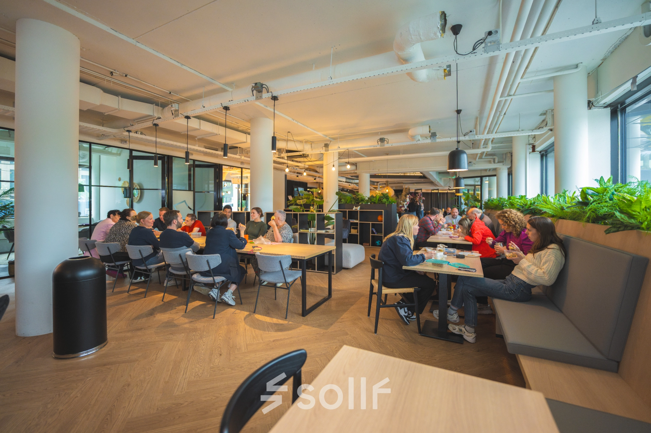 A bright office space at Luttenbergweg 8, Amsterdam South East, featuring modern furnishings with groups of people collaborating. Ideal for those seeking an engaging office space rental.