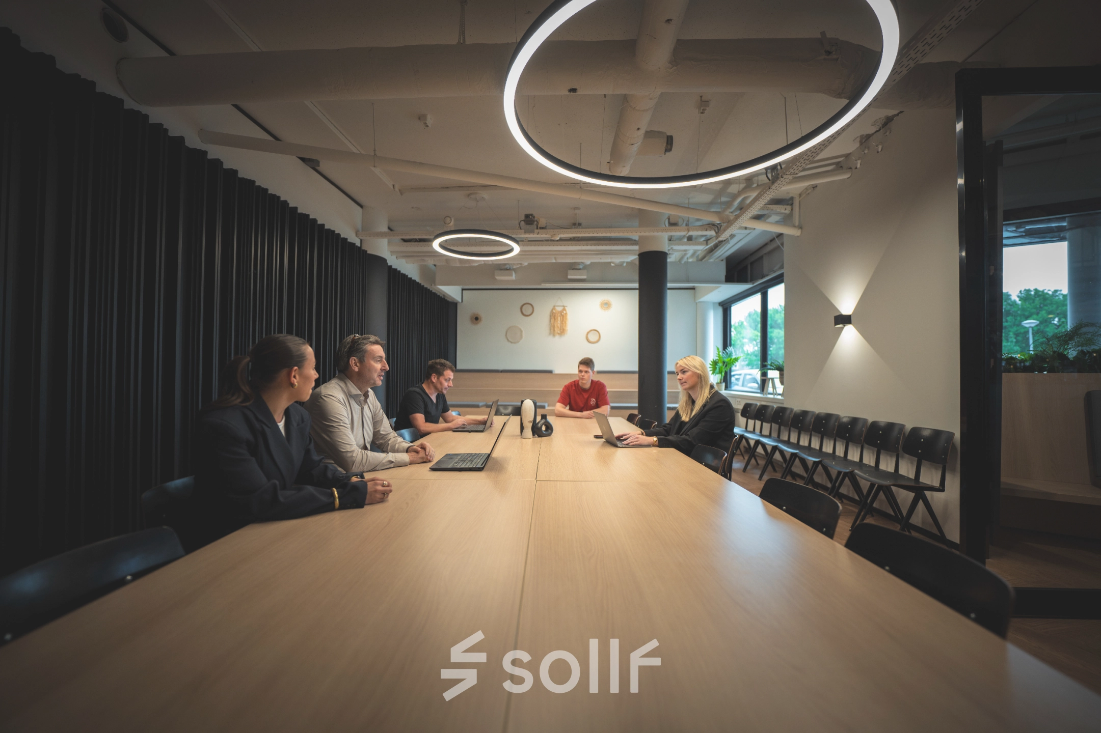 Individuals engaged in a meeting at a long table in a modern office space located at Luttenbergweg 8, Amsterdam South East, ideal for office space rental.
