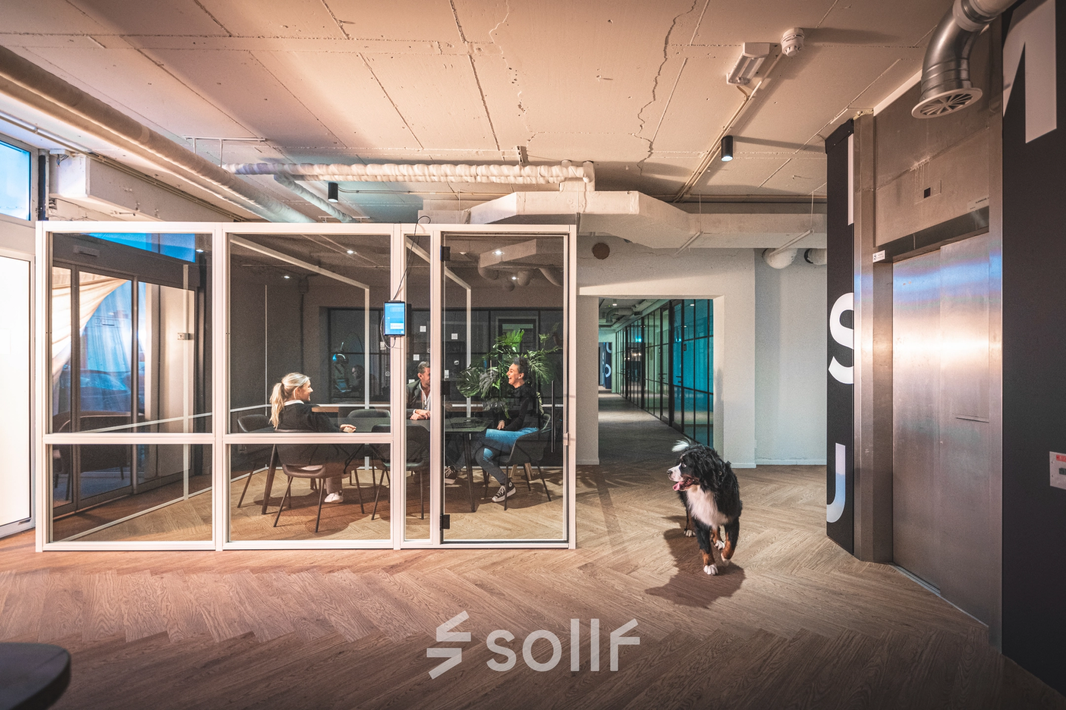 Modern office interior at Luttenbergweg 8, Amsterdam South East, featuring a meeting room with people engaged in discussion, highlighting a vibrant option for office space rental.
