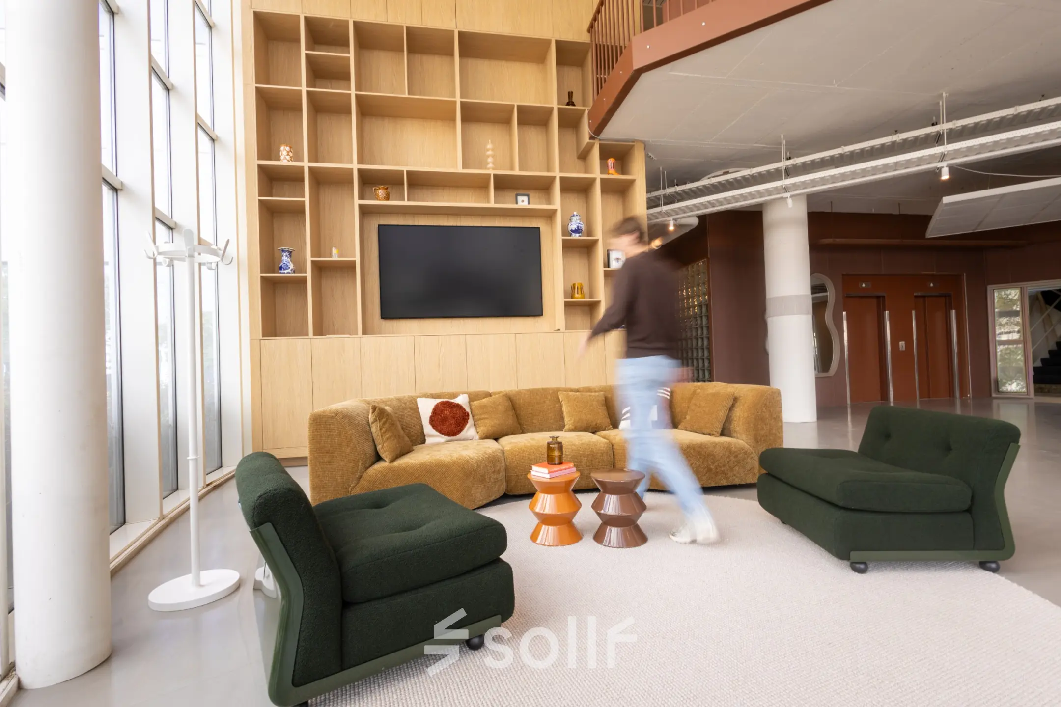 Modern office lounge at Luttenbergweg 8, Amsterdam South East, featuring stylish seating around a flat-screen TV, ideal for office space rental.