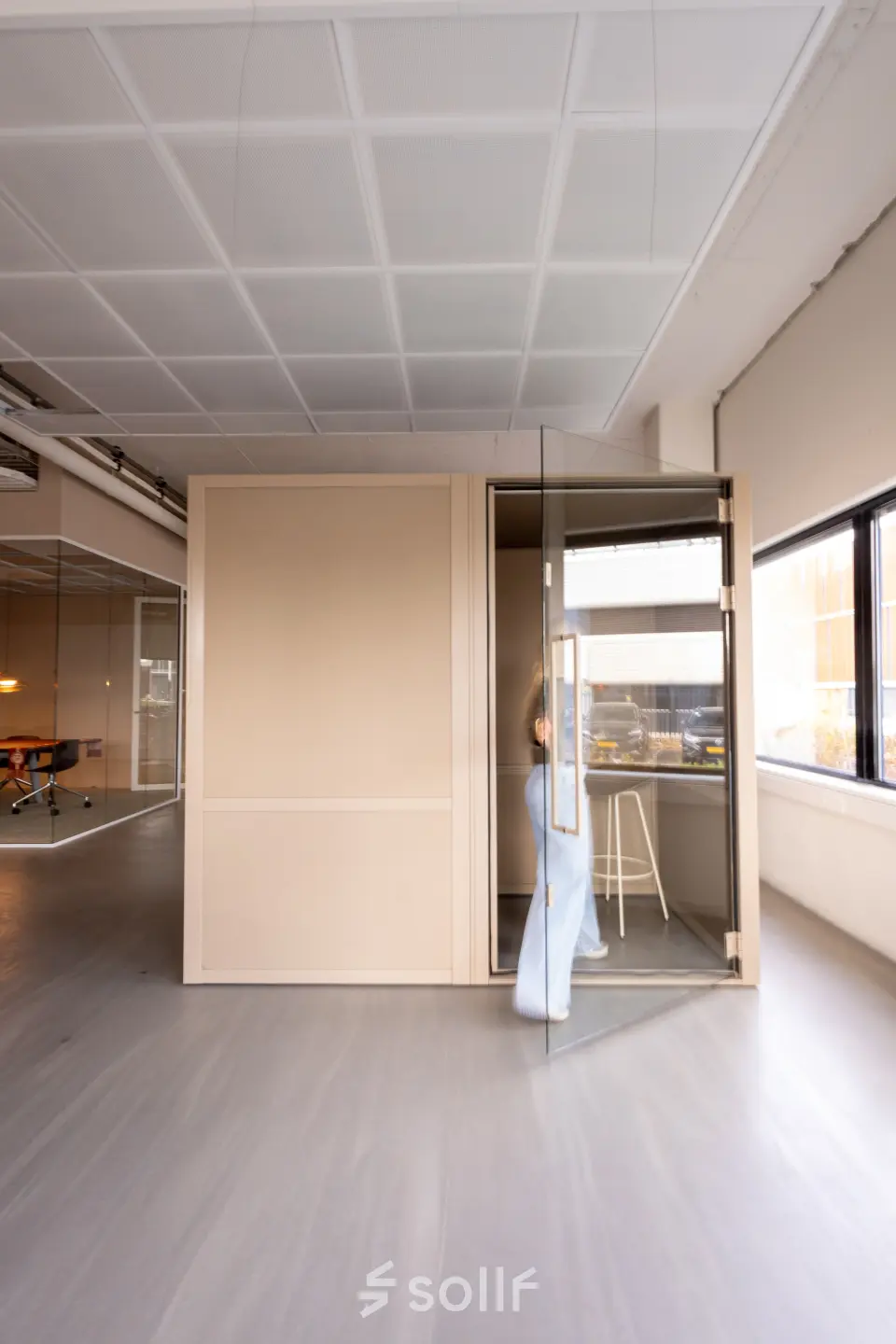 Office space at Luttenbergweg 8, Amsterdam South East, featuring a person entering a private pod with a stool nearby, available for rent.