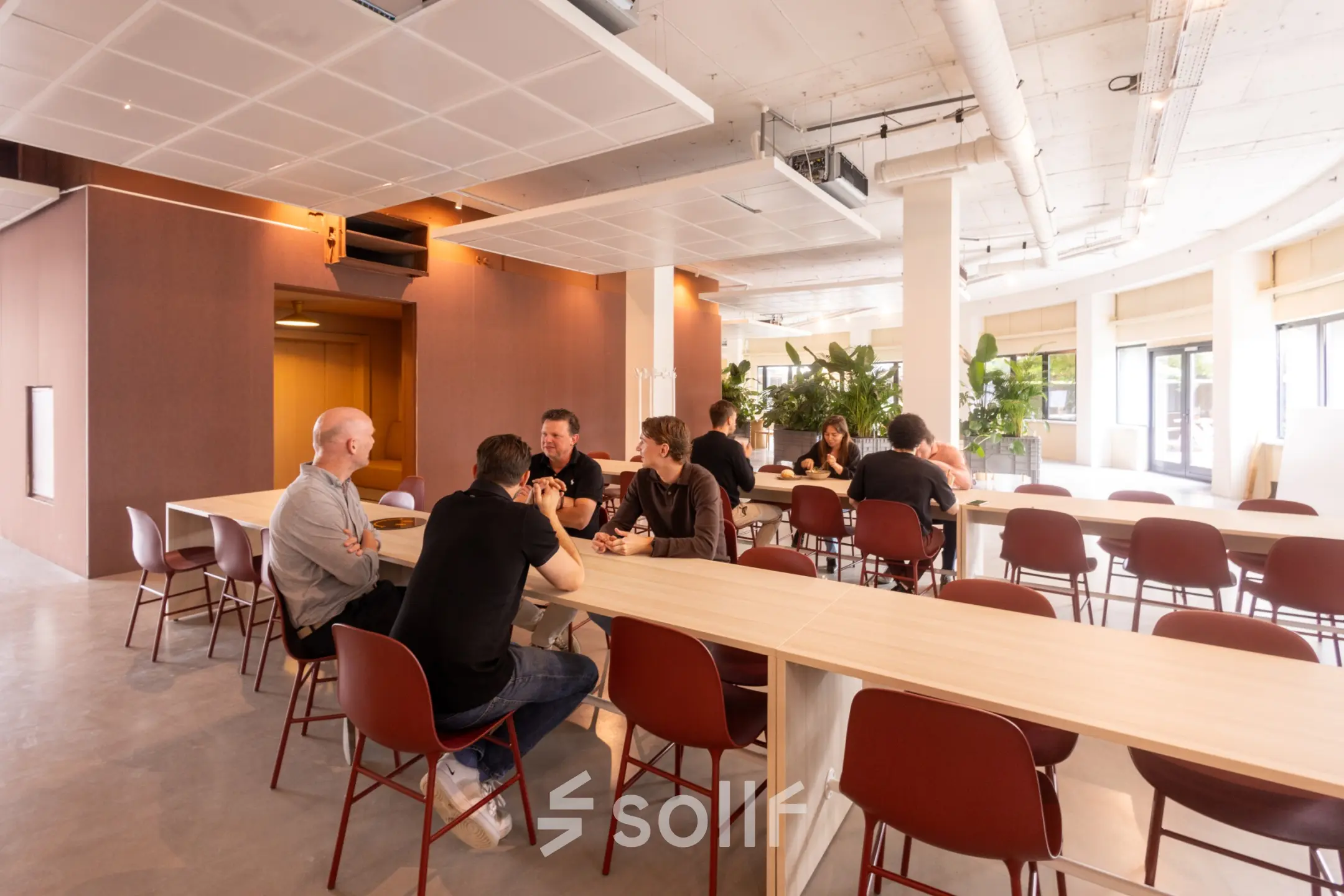 Modern furnished office space at Luttenbergweg 8, Amsterdam South East, featuring people engaged in collaborative work at tables, ideal for office space rental.