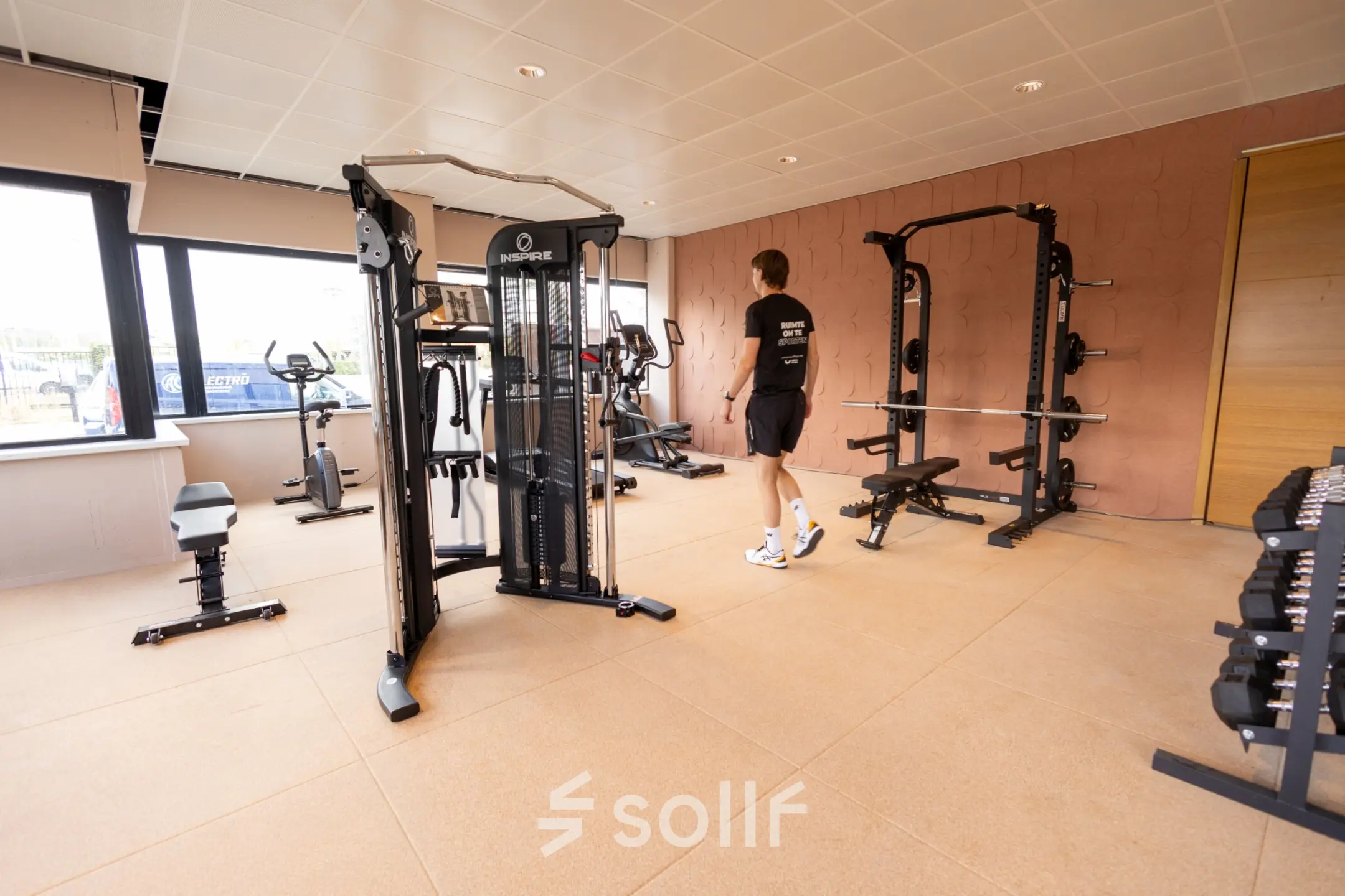 Office gym at Luttenbergweg 8 with fitness equipment and a person working out, ideal for office space rental in Amsterdam South East.