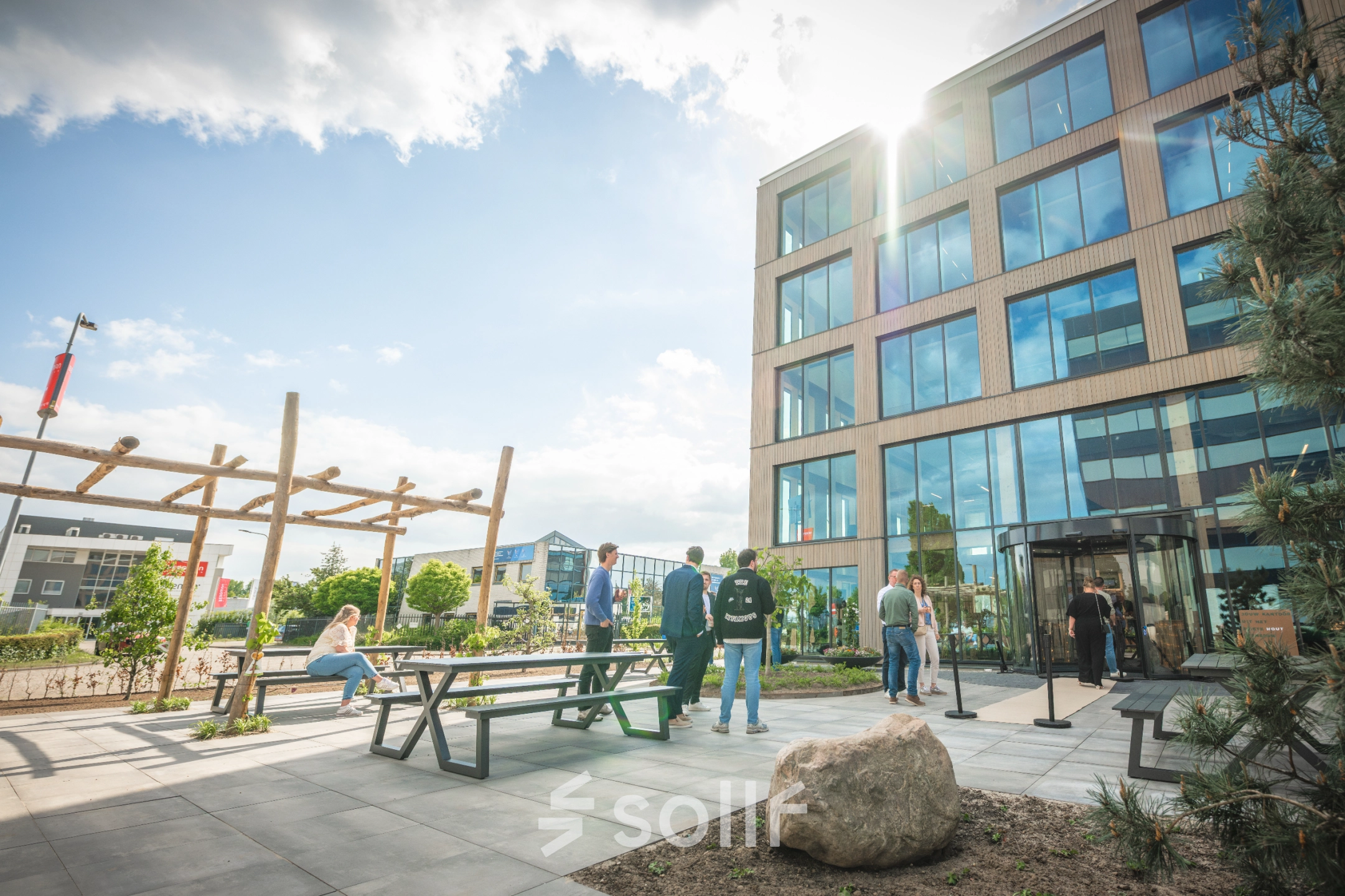 View of Luttenbergweg 8 in Amsterdam South East with people relaxing at picnic tables outside an office to rent.