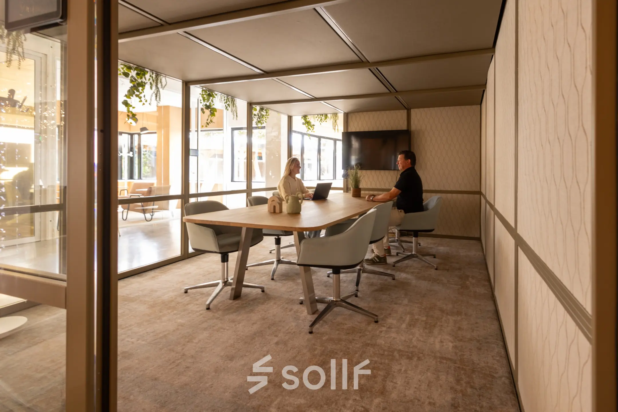 Interior view of a furnished office space at Luttenbergweg 8 in Amsterdam South East, featuring two people engaged in a meeting. This office space rental offers a comfortable environment for business activities.