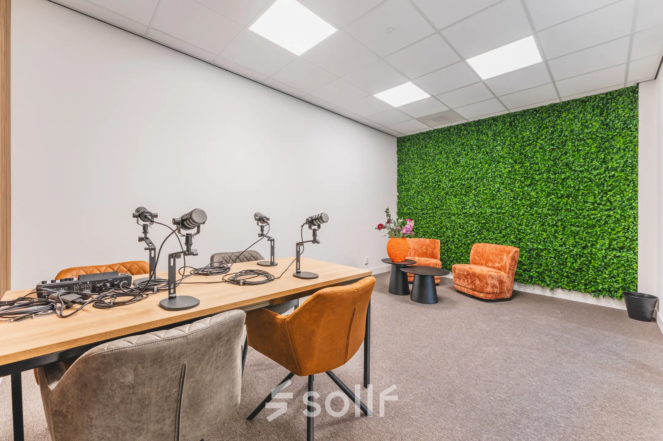 Furnished office space at Paasheuvelweg 20, Amsterdam South East, featuring a modern meeting table with microphones and vibrant chairs against a backdrop of a green wall.