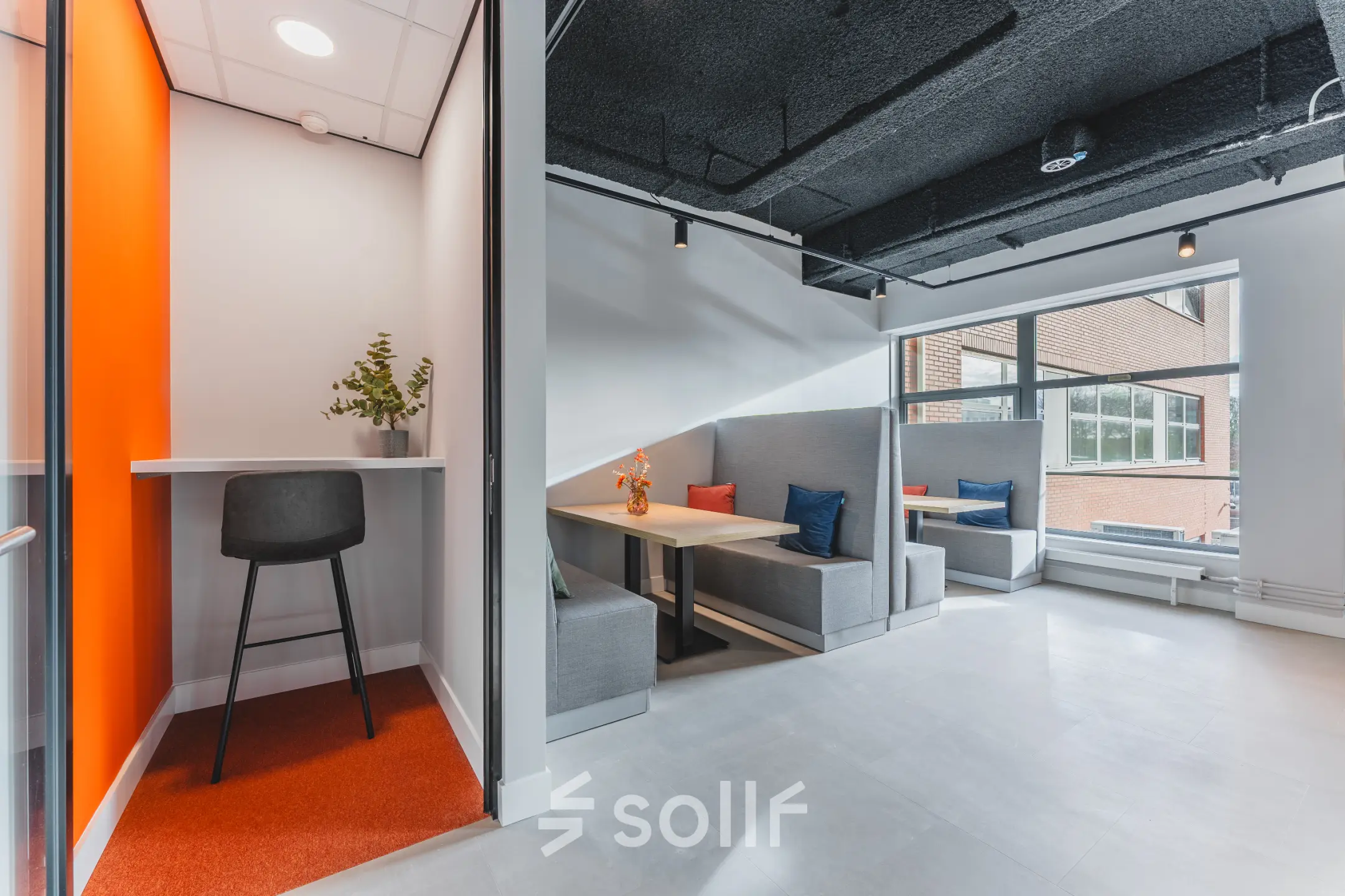 Modern office space at Paasheuvelweg 20, Amsterdam South East, with various seating options available for rent, including cozy booths and a high stool. Bright and inviting area for office space rental.