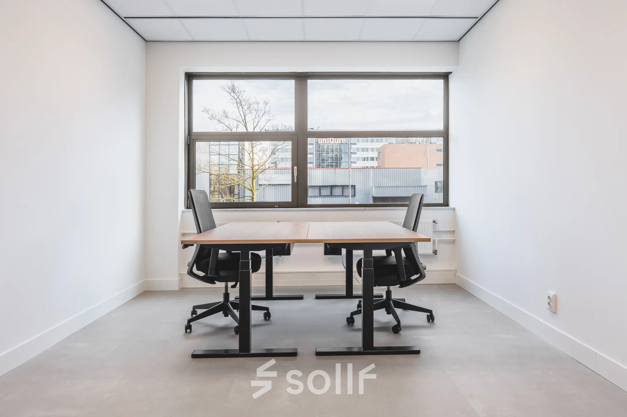 Bright office space at Paasheuvelweg 20, Amsterdam South East, featuring two desks and chairs near a large window. Ideal for office space rental.