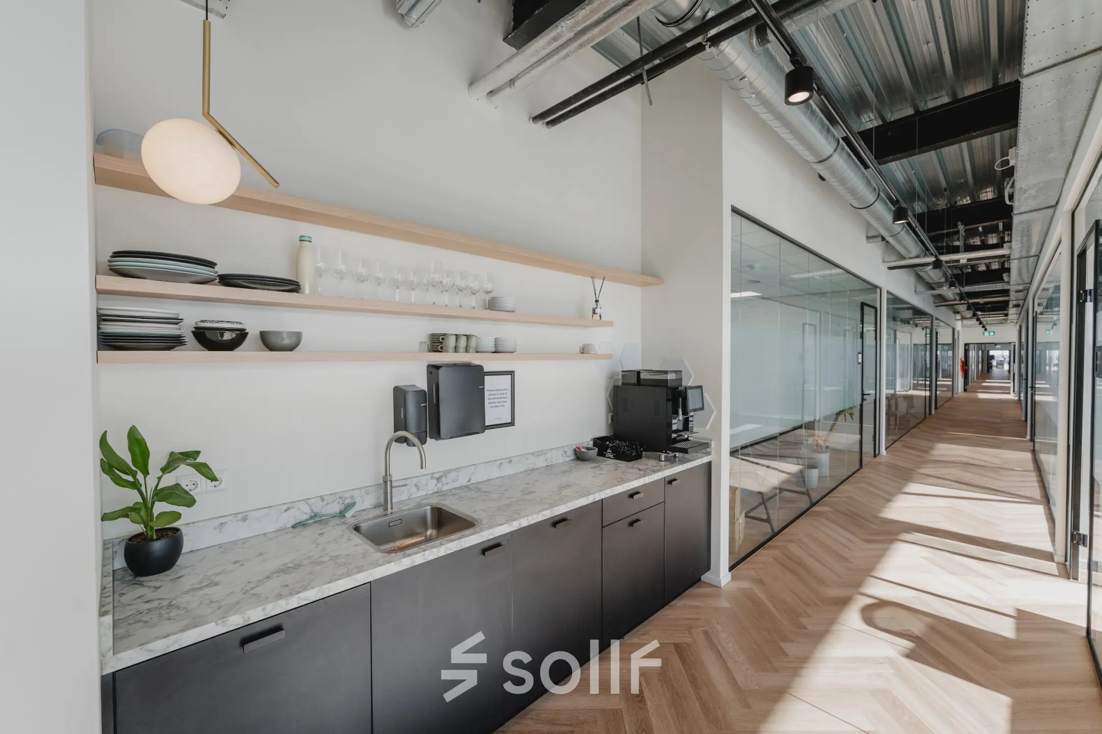 Modern office interior at Bos en Lommerplein 280 with sleek cabinetry, a marble countertop, and glass partitions, ideal for office space rental in Amsterdam West.