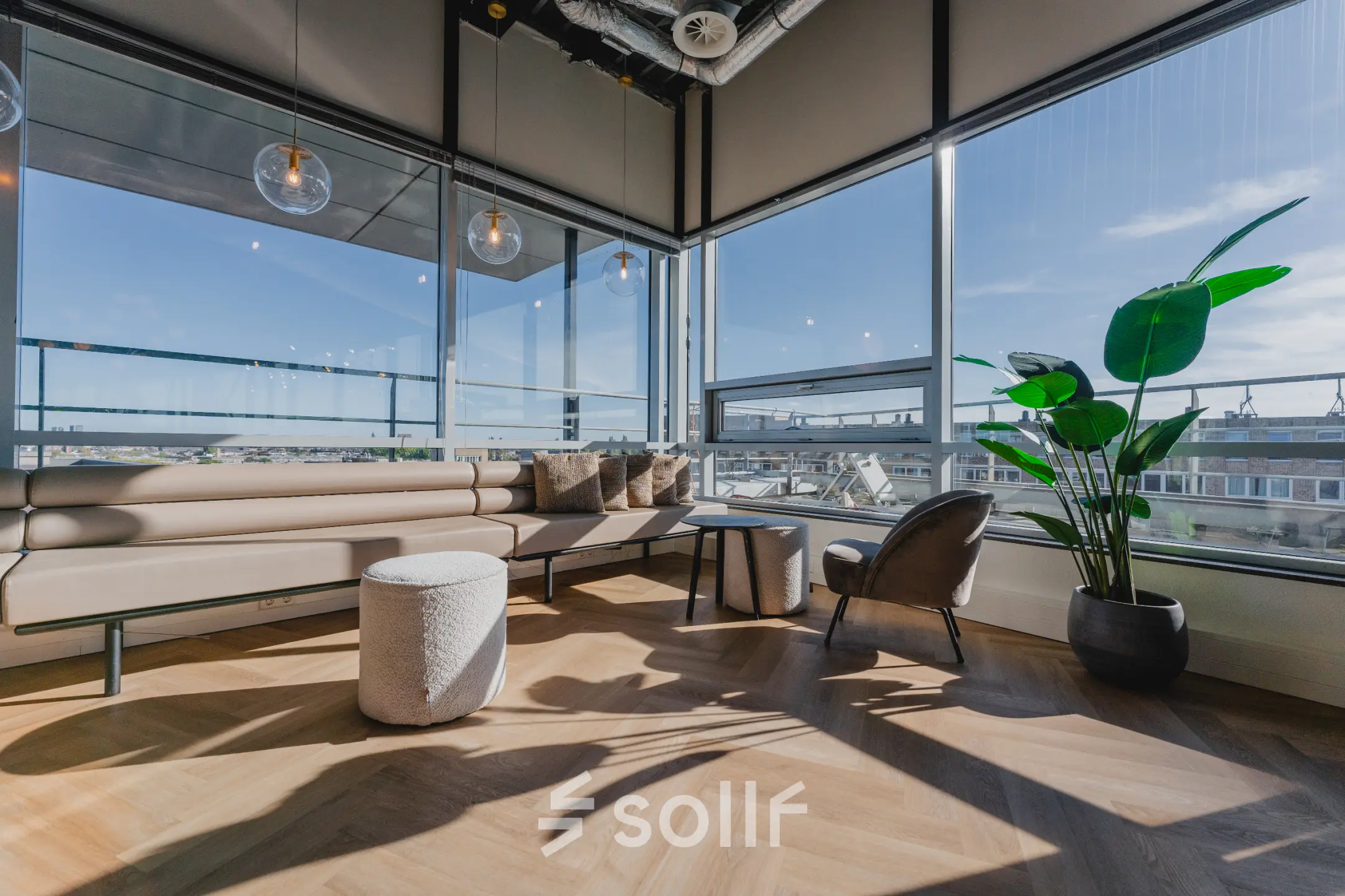 Bright office lounge at Bos en Lommerplein 280 in Amsterdam West with modern furnishings, large windows offering city views, and a relaxed seating area. Ideal for office space rental.
