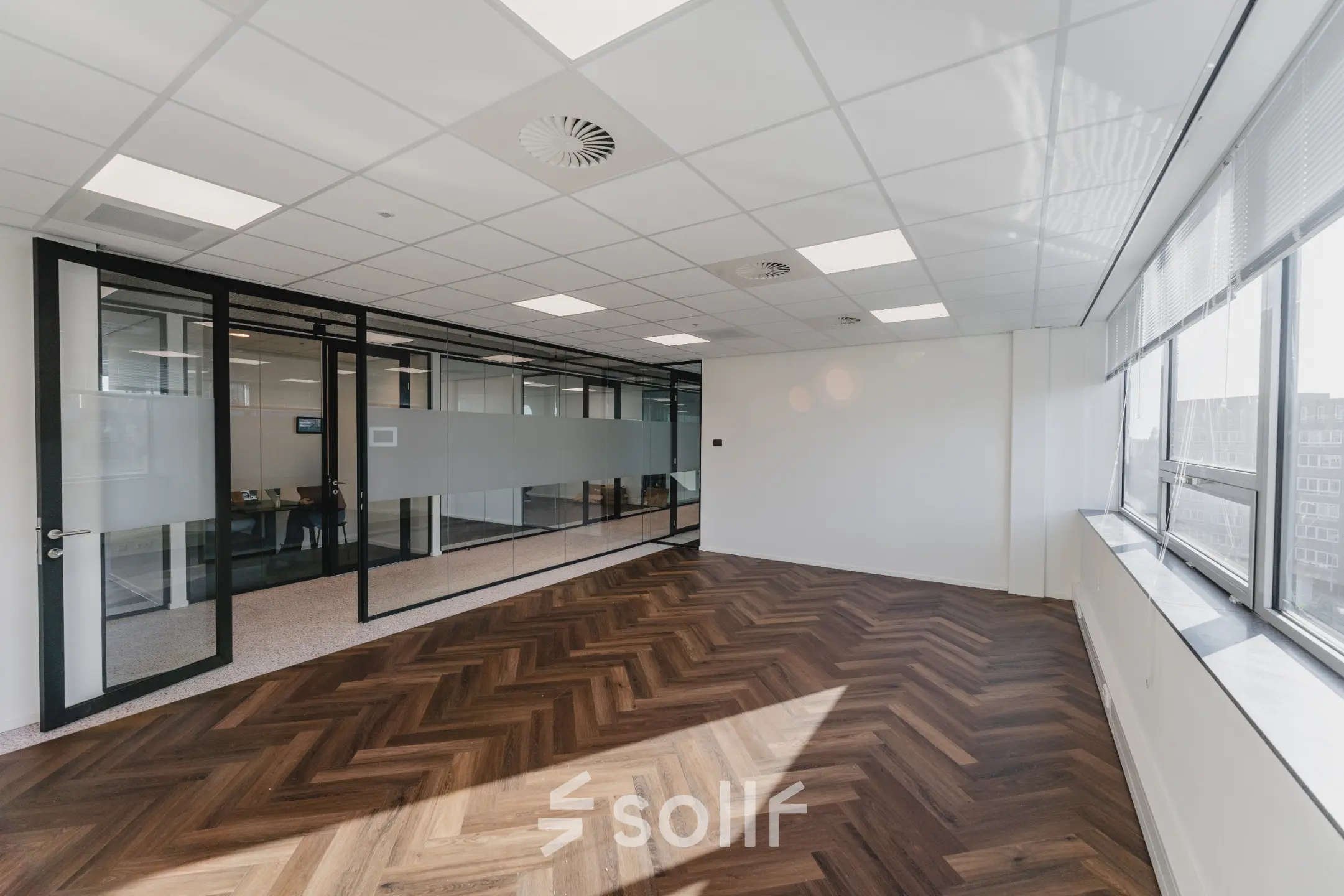 Spacious, unfurnished office to rent at Bos en Lommerplein 280 in Amsterdam West with large windows and wooden flooring.