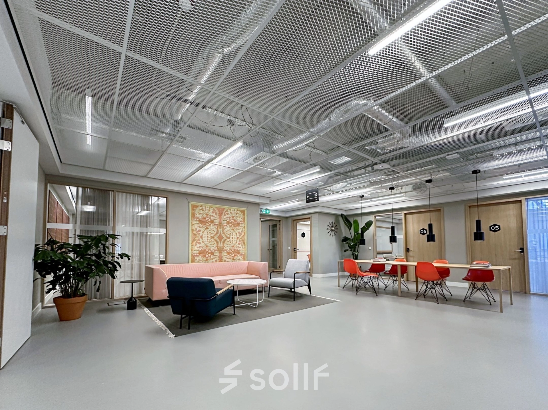 Modern office space at Haarlemmerweg 331, Amsterdam West, featuring a chic seating area and vibrant red chairs ideal for rental.