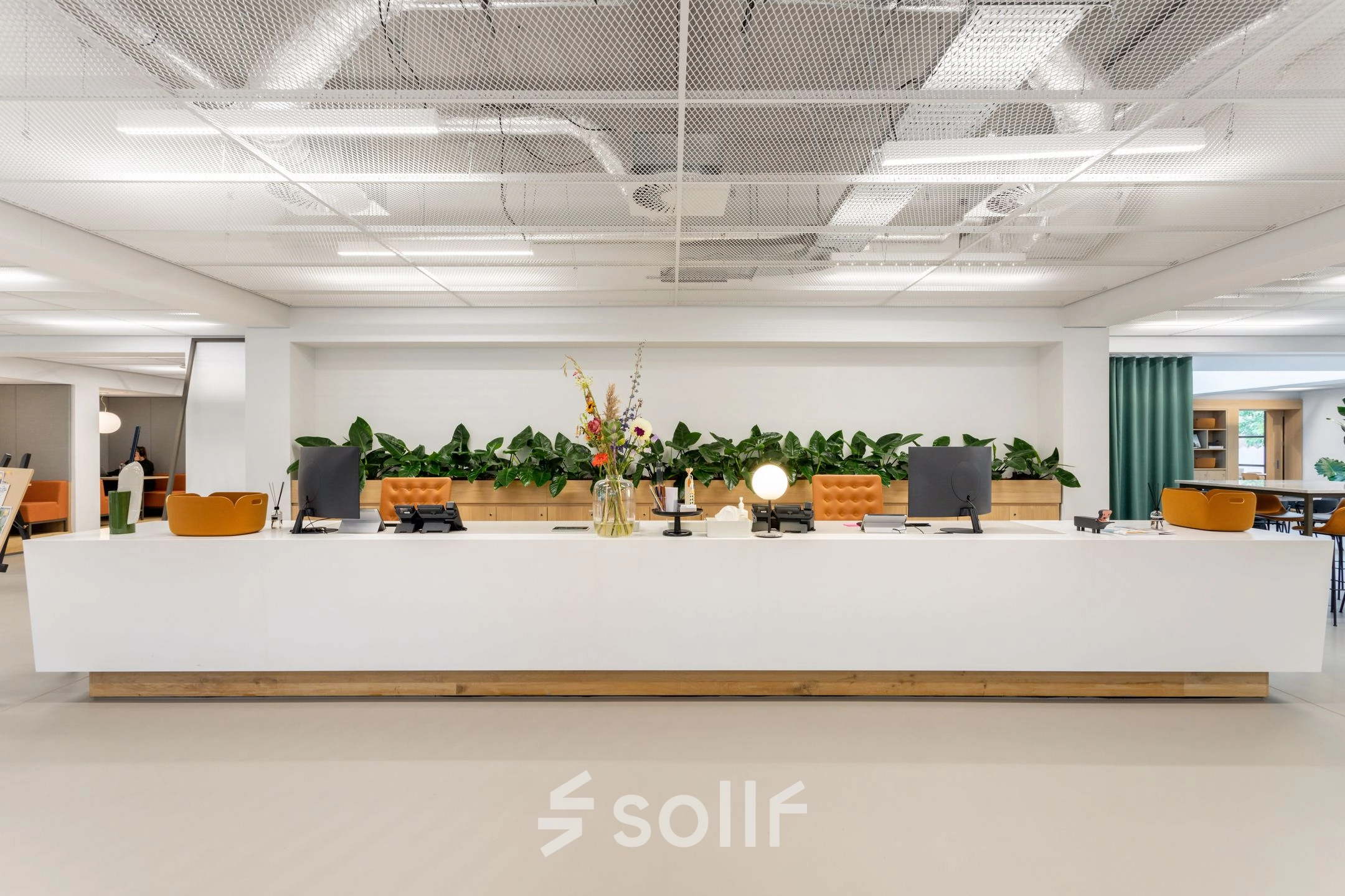 Spacious office in Amsterdam West with a modern, furnished reception area featuring a large desk and green accents. Ideal for office space rental.