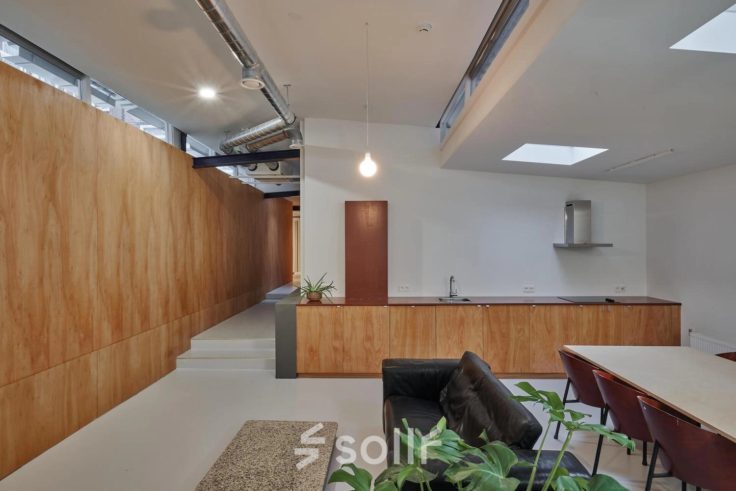 Modern office space with wood paneling and skylights at Hondiusstraat 7H in Amsterdam West, featuring a sleek kitchenette and a cozy seating area. Perfect for office space rental.